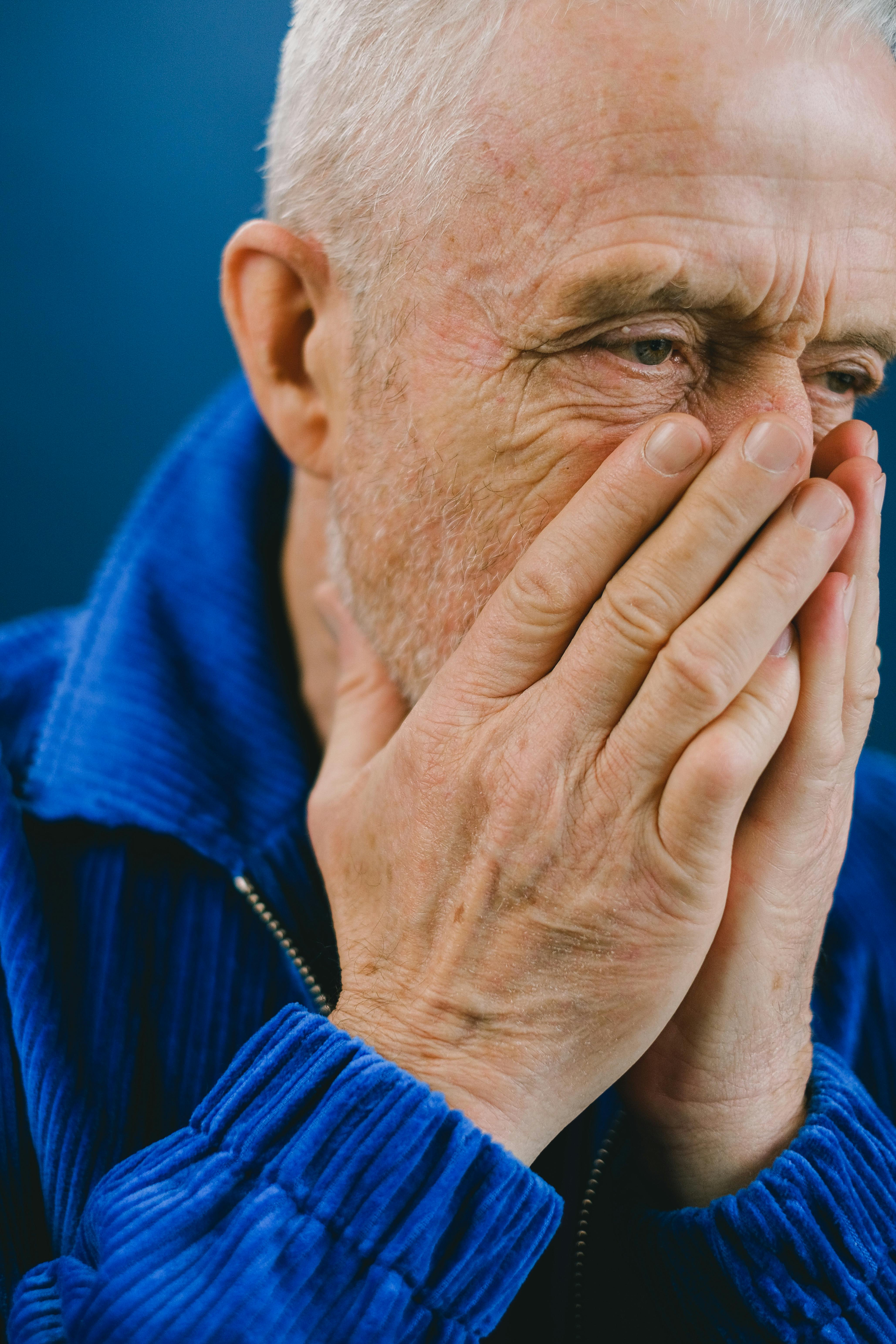 Un homme âgé bouleversé se couvrant la bouche et le nez avec ses mains | Source : Pexels