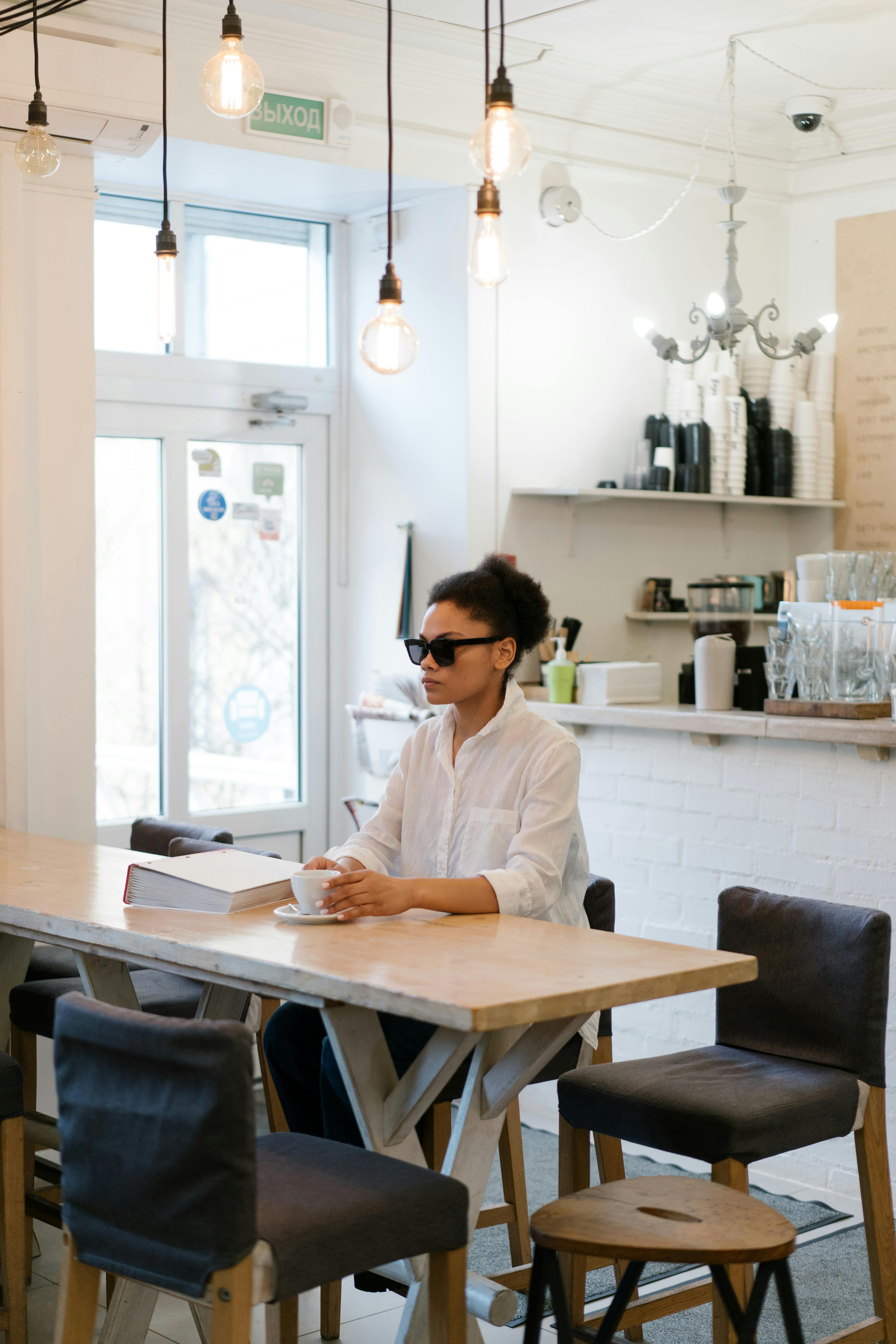 Une femme portant des lunettes de soleil assise à une table dans un café | Source : Pexels