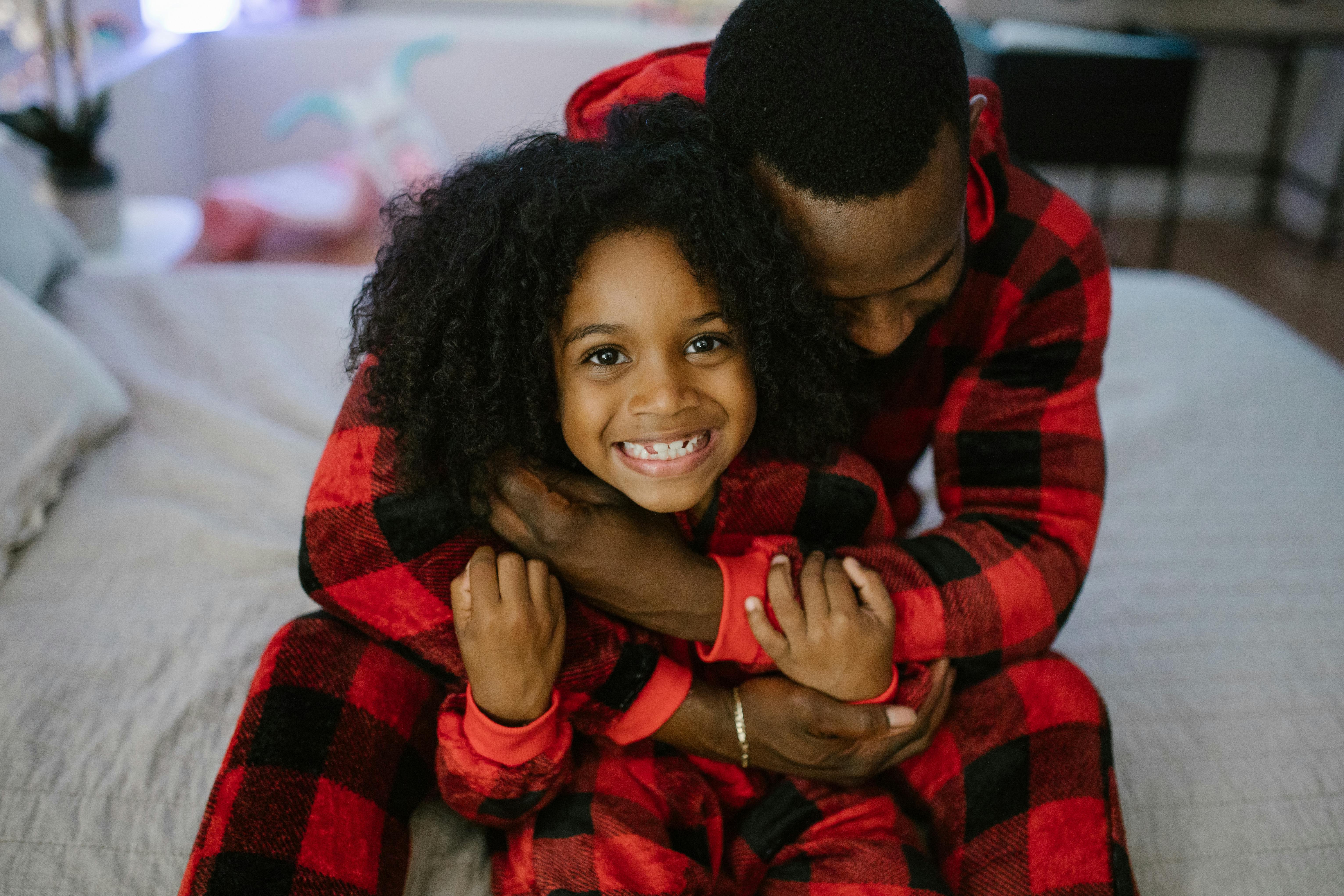 Un homme serrant sa fille dans ses bras tout en portant un pyjama assorti | Source : Pexels
