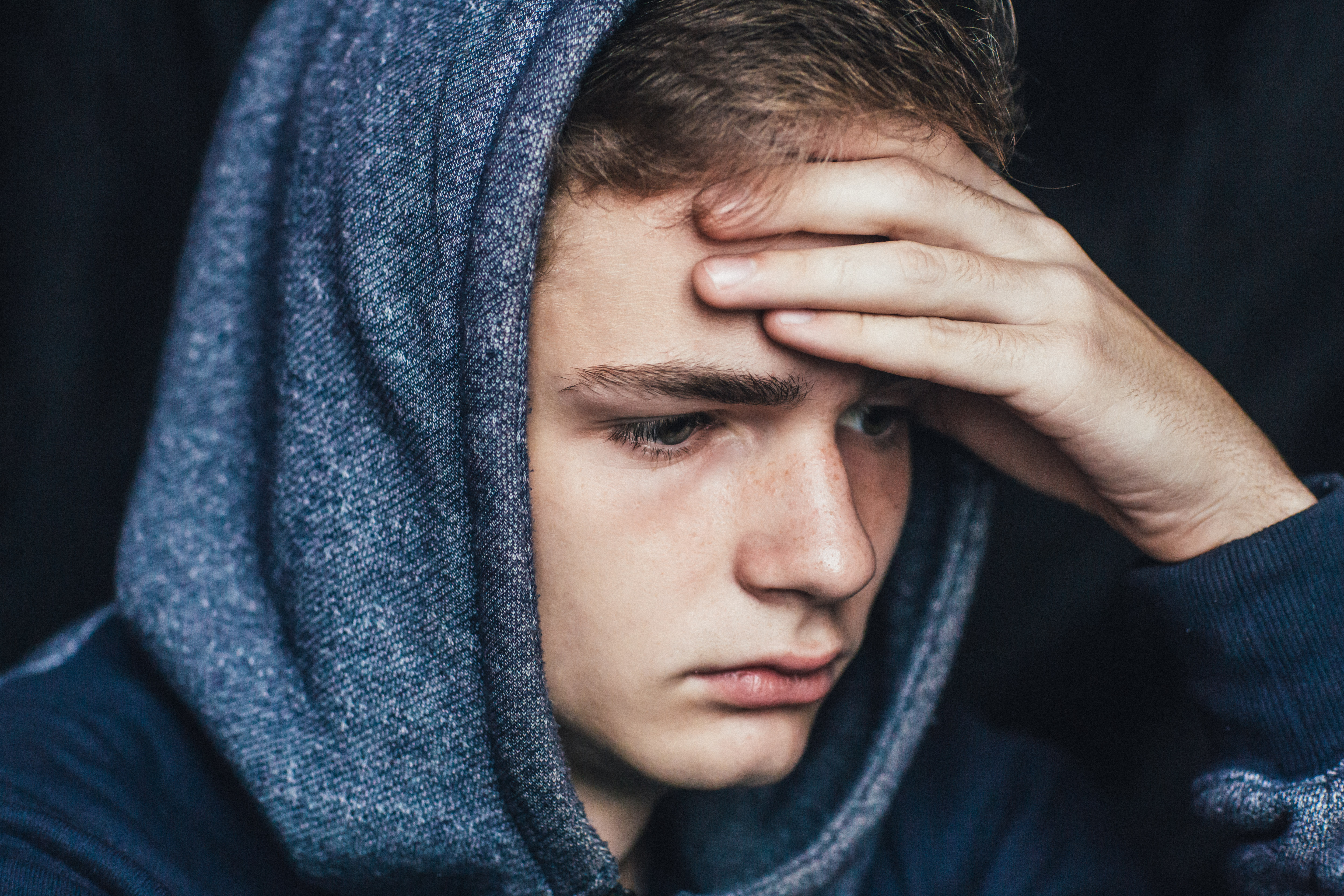 Un jeune homme triste vêtu d'un sweat à capuche bleu | Source : Shutterstock