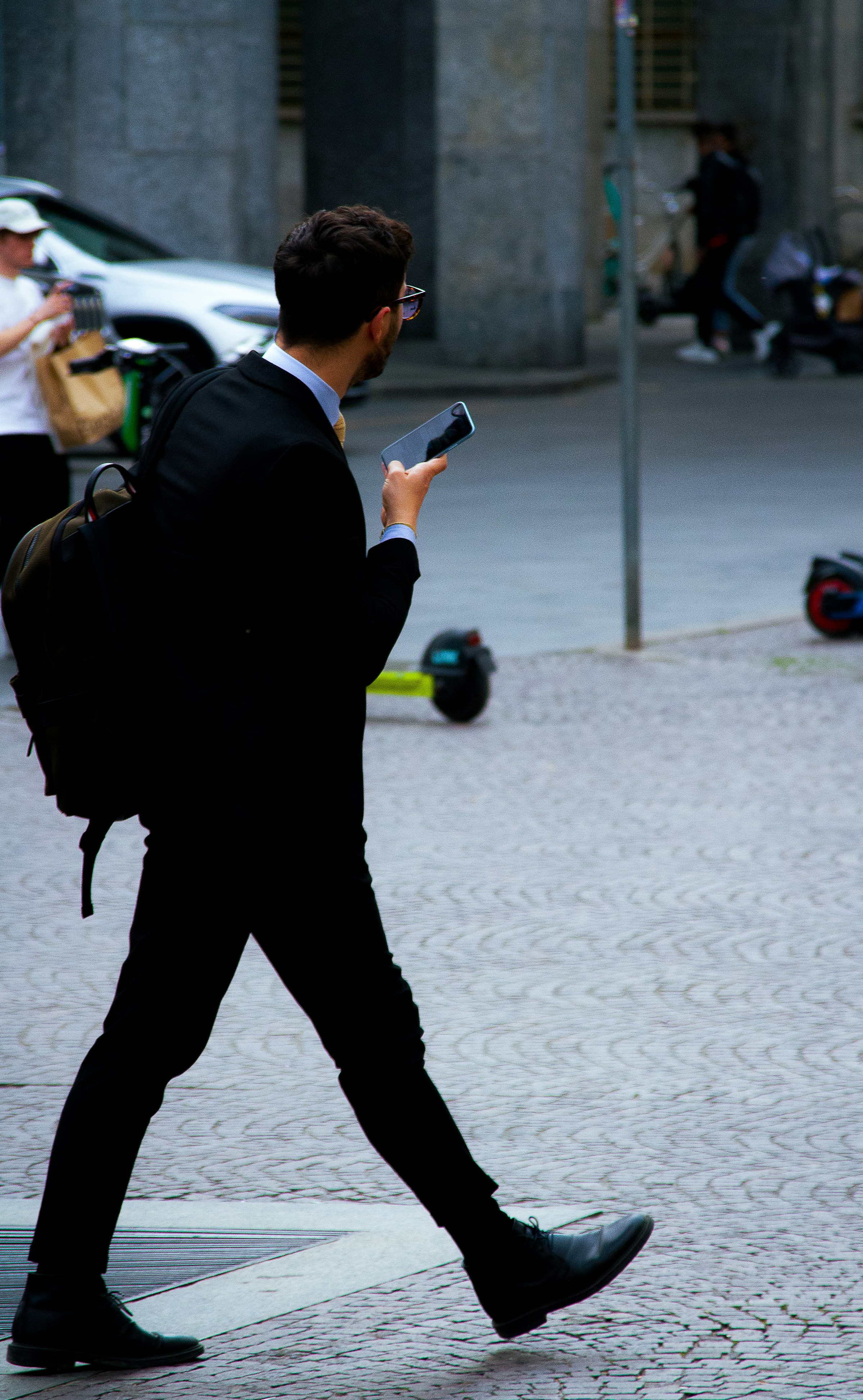 Homme d'affaires marchant dans la rue avec son téléphone à la main | Source : Unsplash