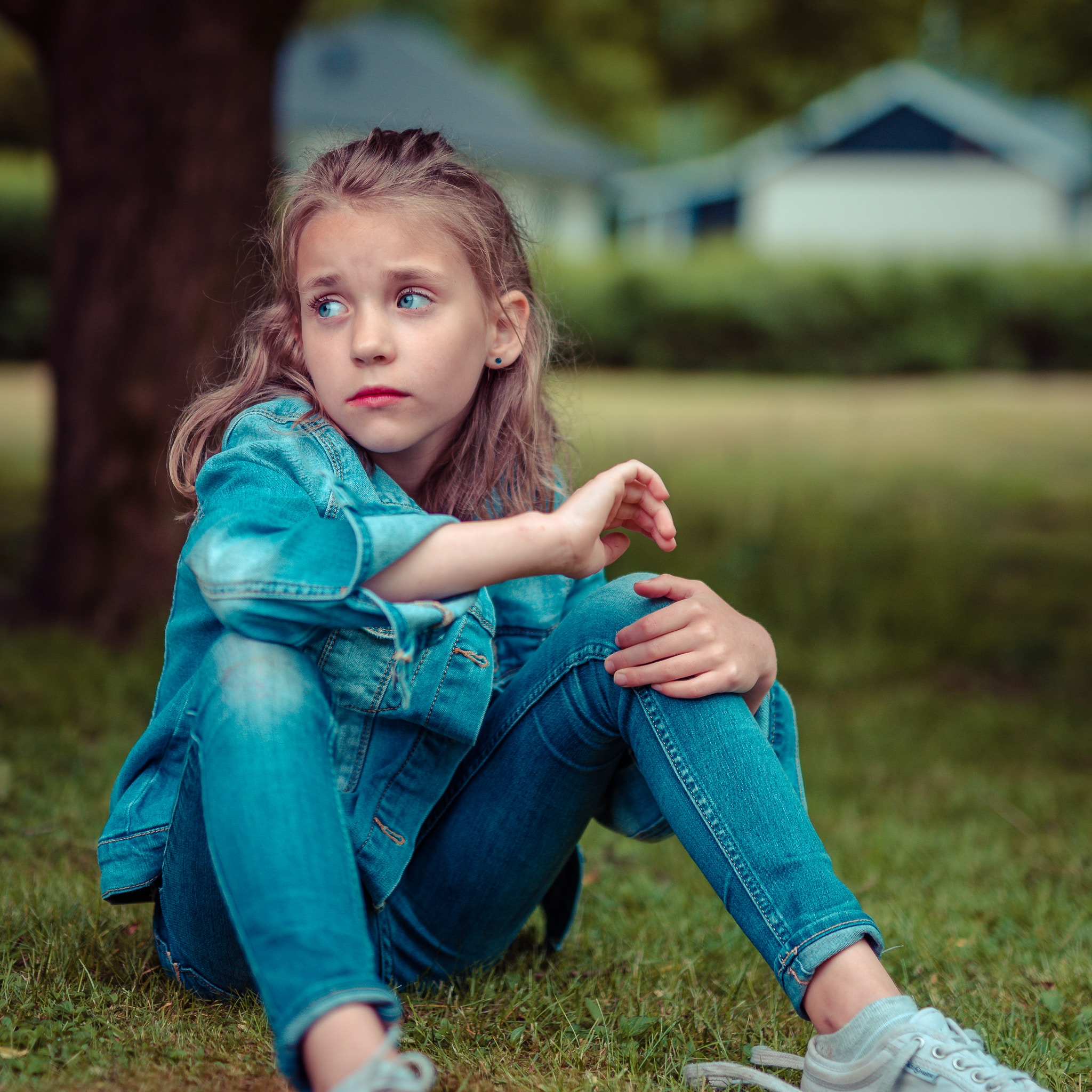 Une petite fille triste assise dans l'herbe le 13 juin 2017. | Source : Unsplash