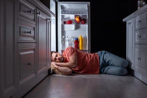 Un homme endormi devant un frigo ouvert | Photo : Shutterstock.