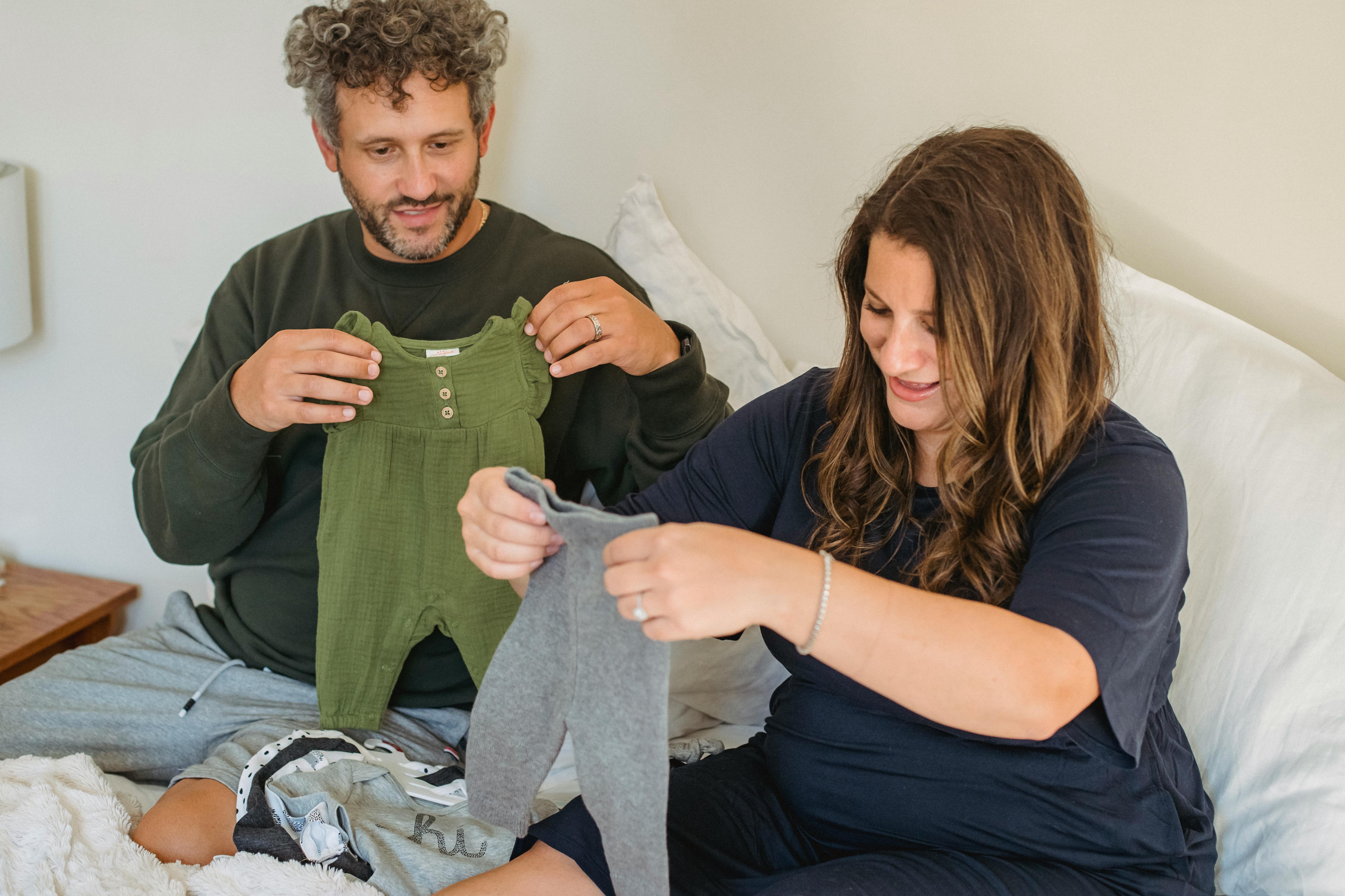 Un couple regardant des vêtements de bébé | Source : Pexels