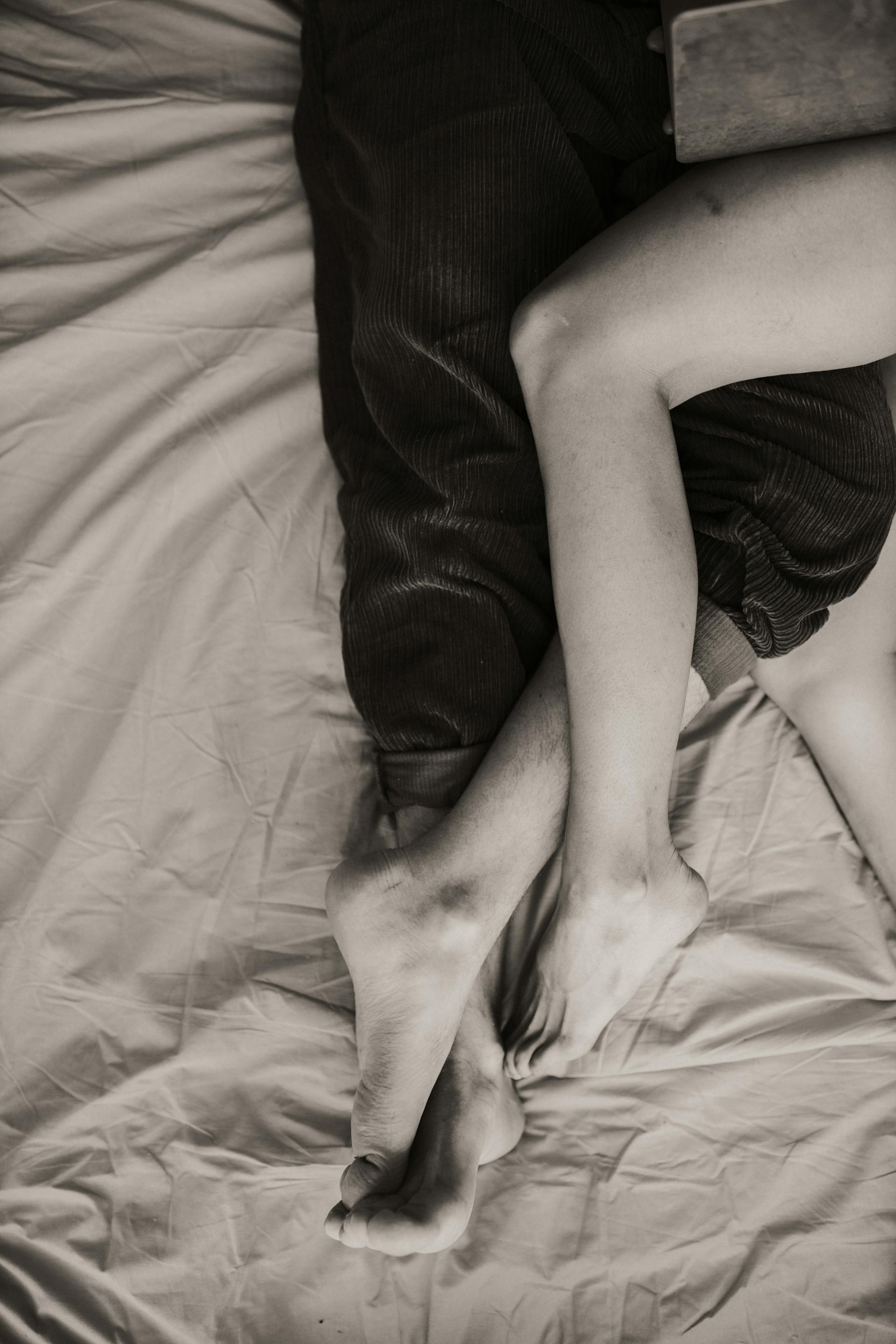 Deux personnes allongées sur un lit avec leurs jambes entrelacées | Source : Pexels