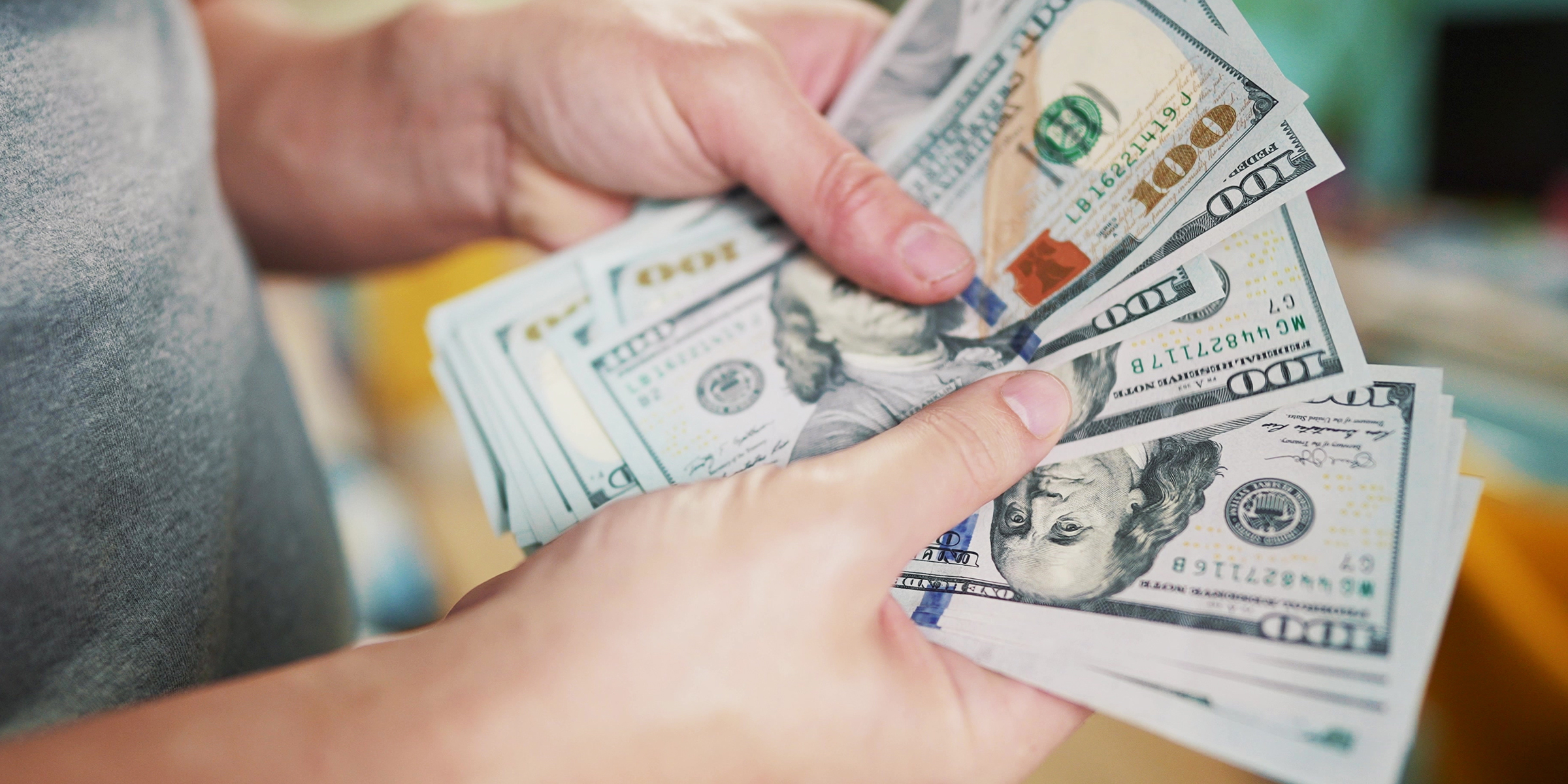 Une personne tenant et comptant une pile de billets de 100 dollars | Source : Shutterstock