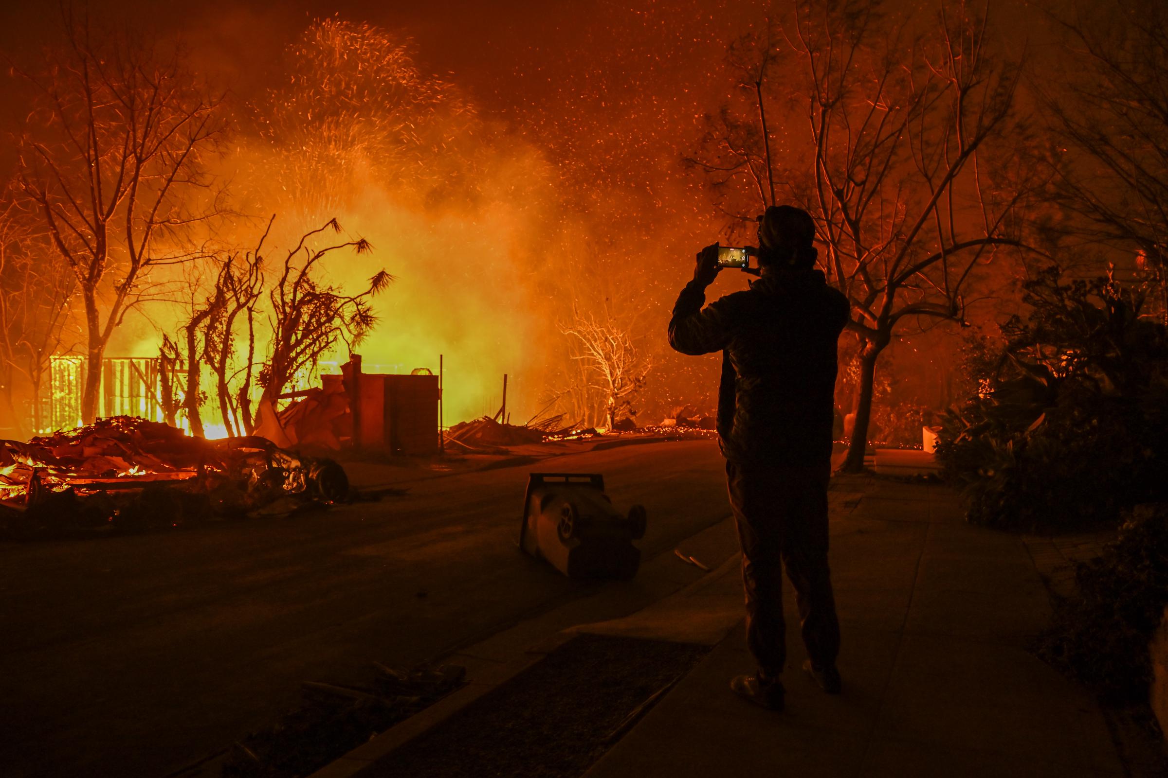 Un civil enregistrant la destruction d'un feu de forêt à Pacific Palisades, en Californie, le 8 janvier 2025. | Source : Getty Images