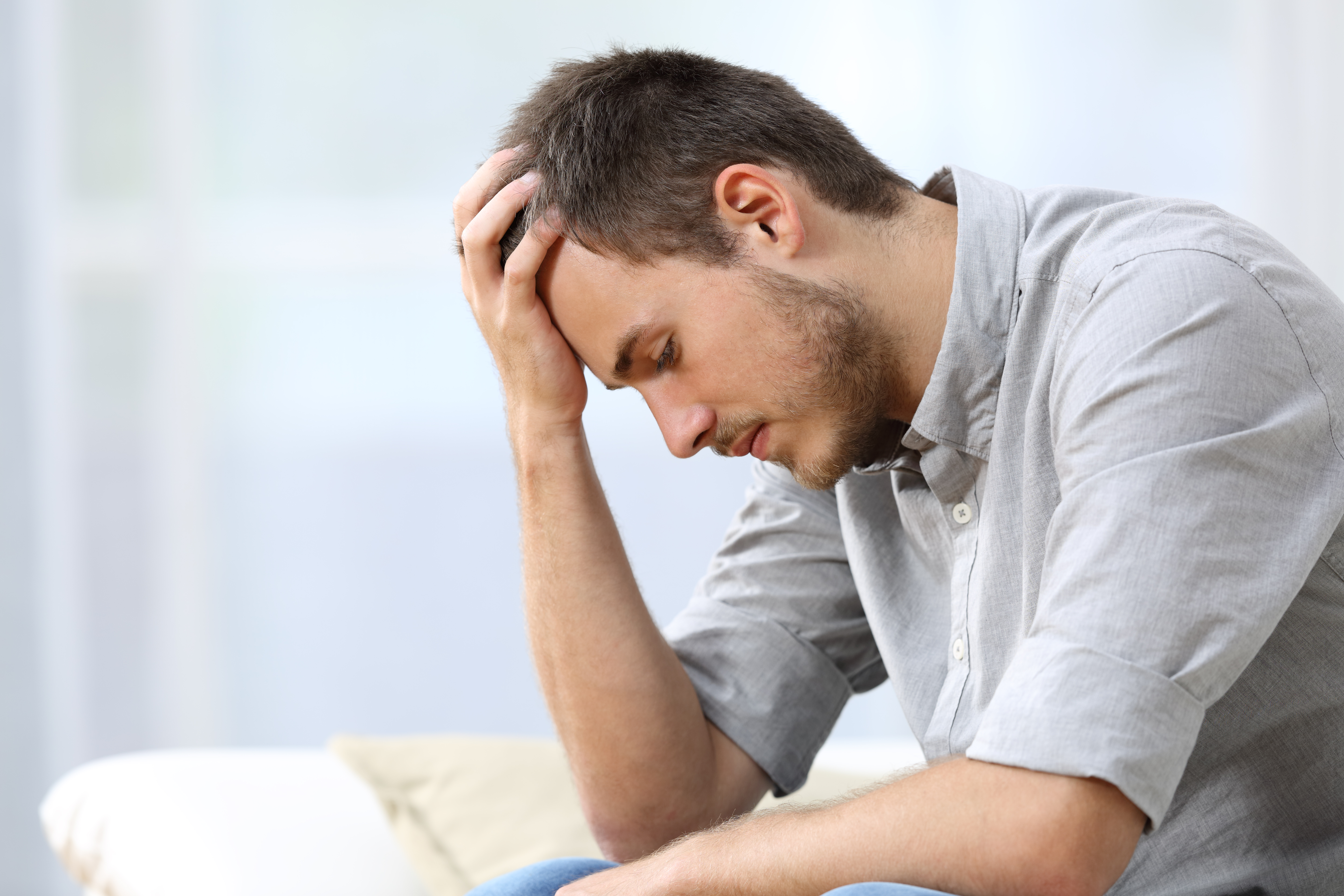 Homme triste assis sur le canapé à la maison | Source : Getty Images