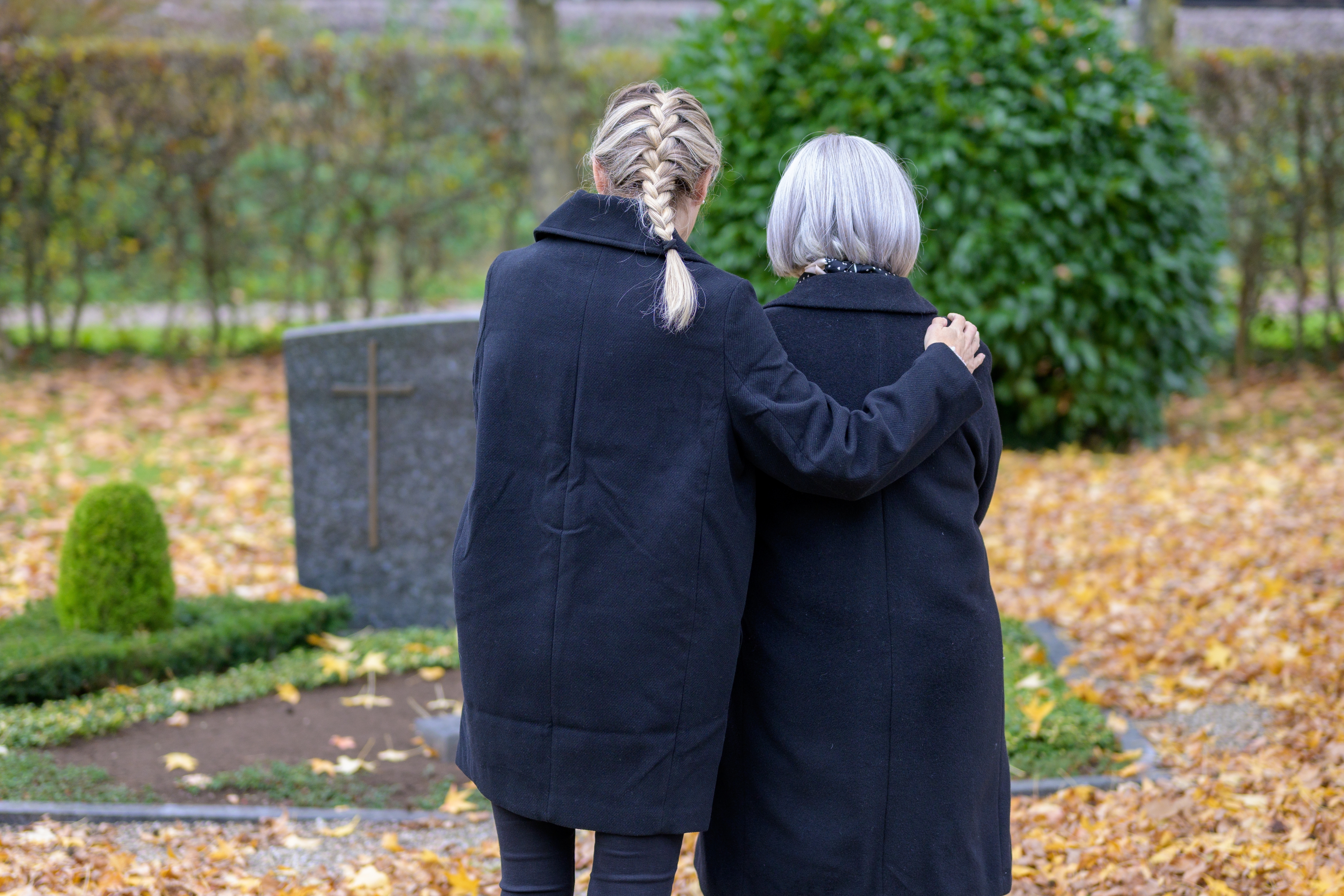 Deux femmes se réconfortent l'une l'autre alors qu'elles se trouvent dans un cimetière | Source : Shutterstock