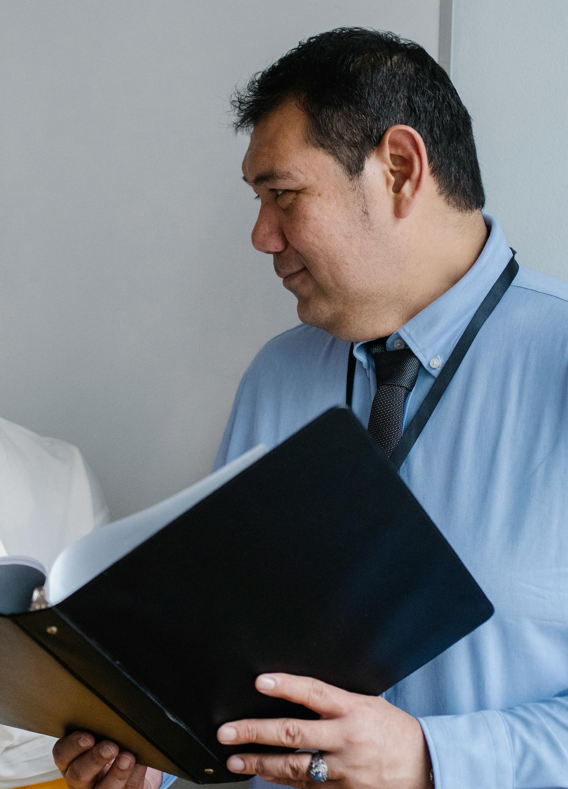 A man holding documents in a folder | Source: Pexels