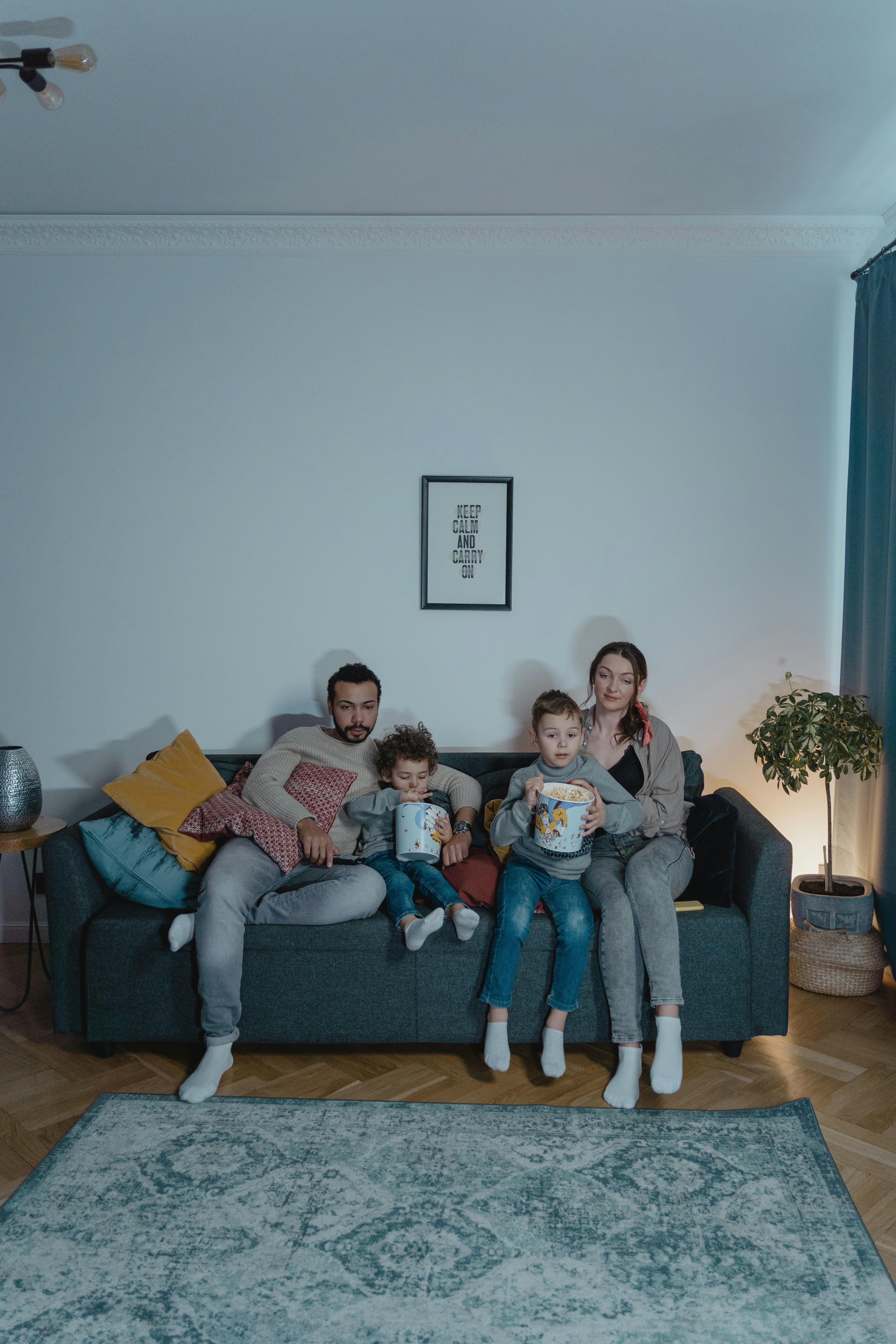 Un couple assis sur le canapé avec ses enfants | Source : Pexels