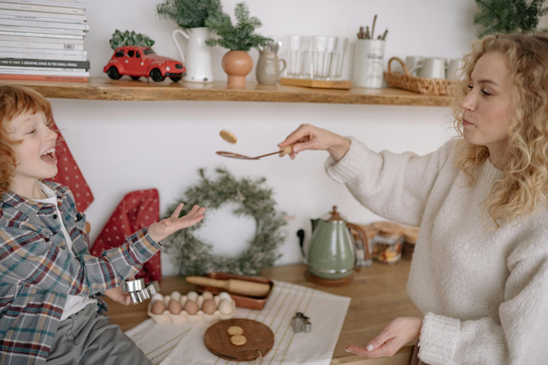 Une femme retourne des biscuits sur une louche tout en s'amusant avec son jeune garçon | Source : Pexels
