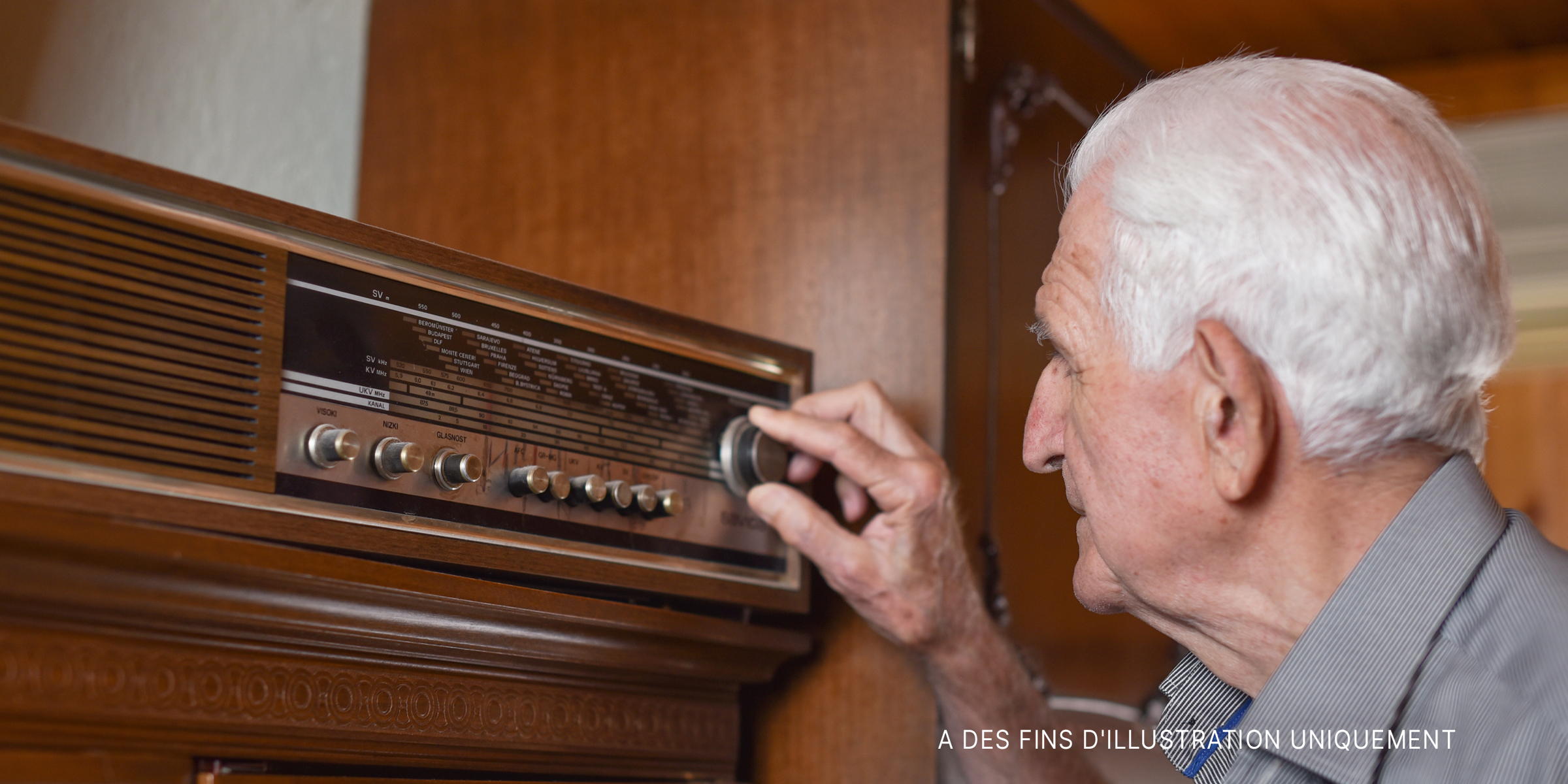 Un homme âgé règle la fréquence d'une radio à l'ancienne | Source : Getty Images