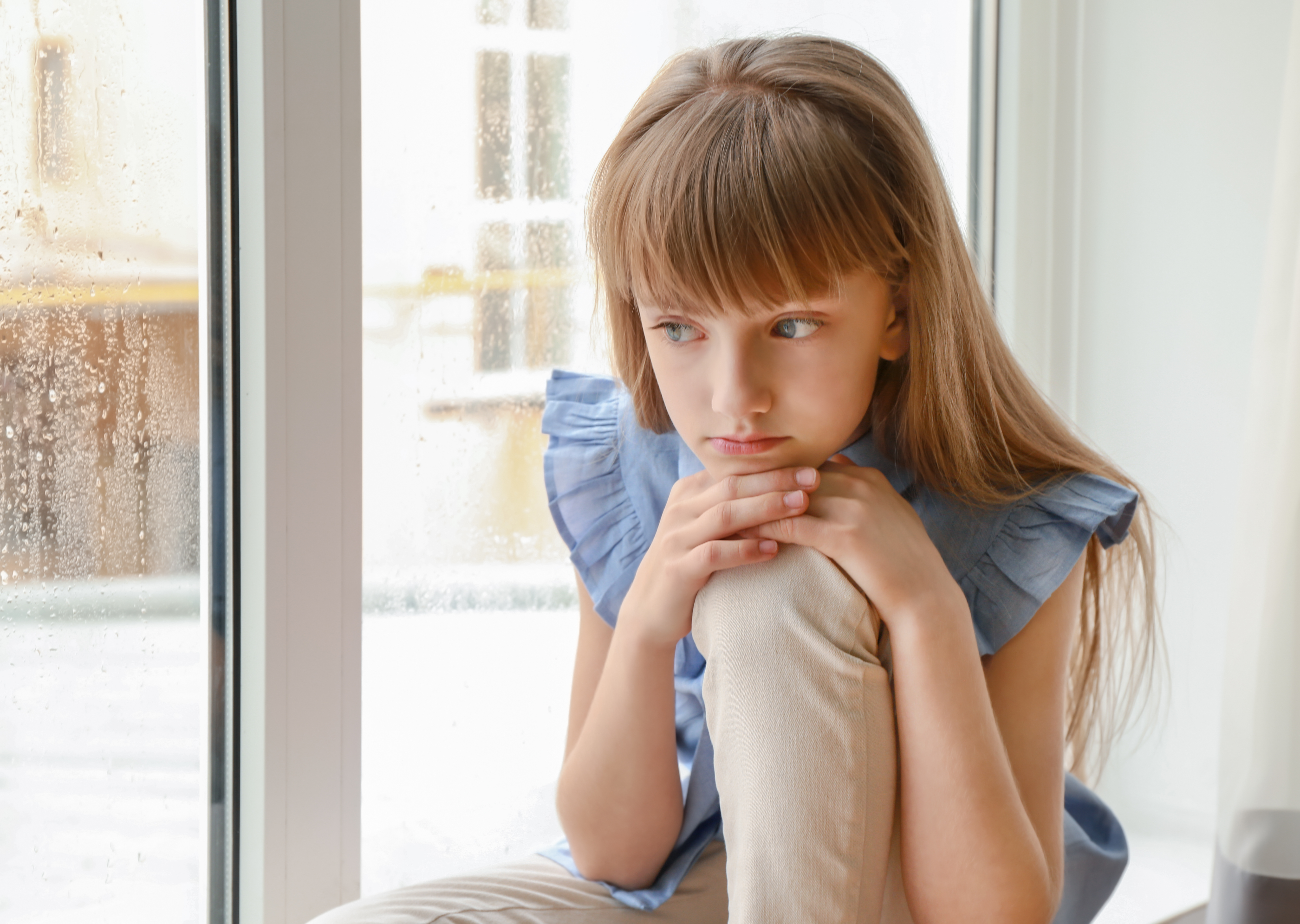 Petite fille boudant près de la fenêtre | Source : Shutterstock