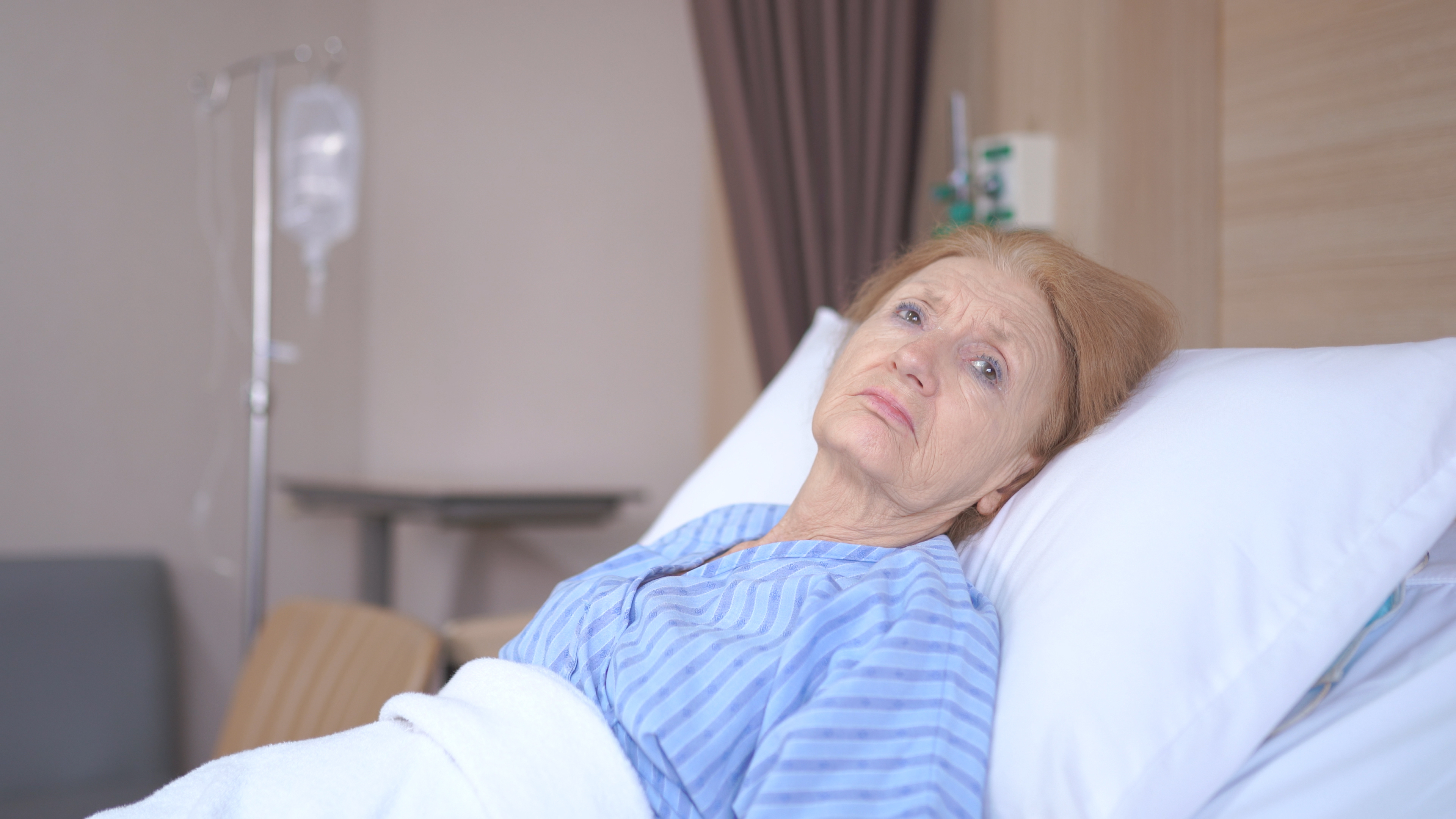 Une femme âgée malheureuse dans un lit d'hôpital | Source : Shutterstock