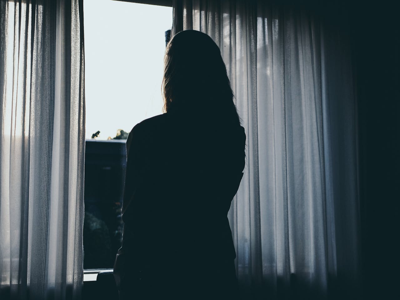 Silhouette d'une femme debout à côté de la fenêtre | Source : Pexels