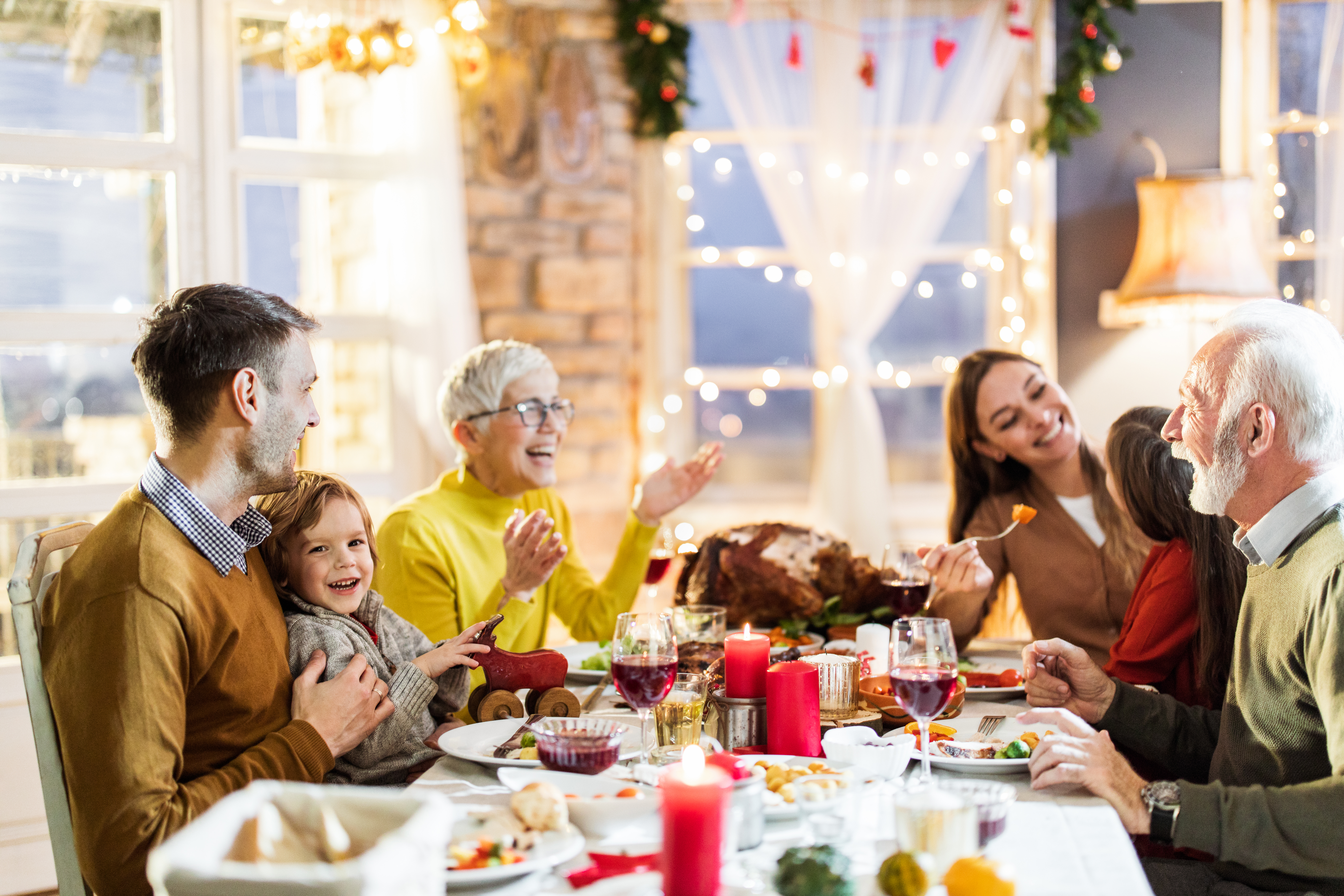Famille multigénérationnelle heureuse en conversation pendant le déjeuner de Thanksgiving à la table à manger | Source : Getty Images