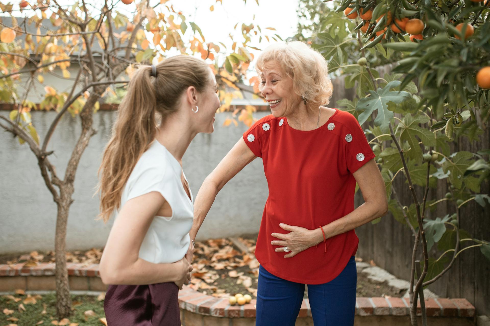 Une femme blonde avec une queue de cheval discute avec une dame âgée dans le jardin | Source : Pexels