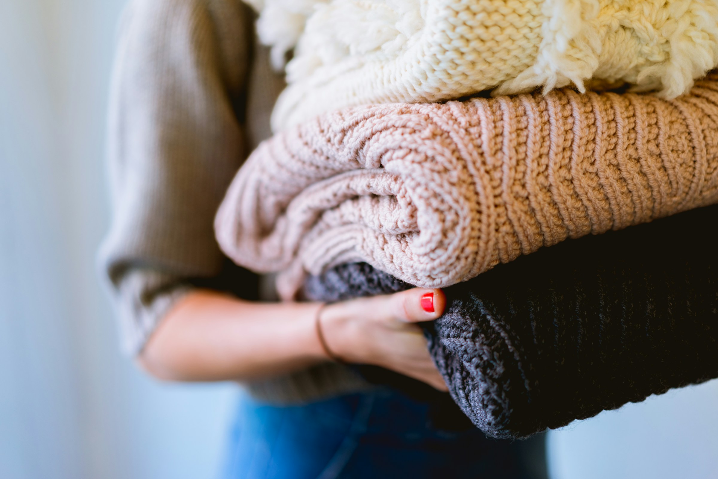 Femme portant une pile de vêtements en laine | Source : Unsplash