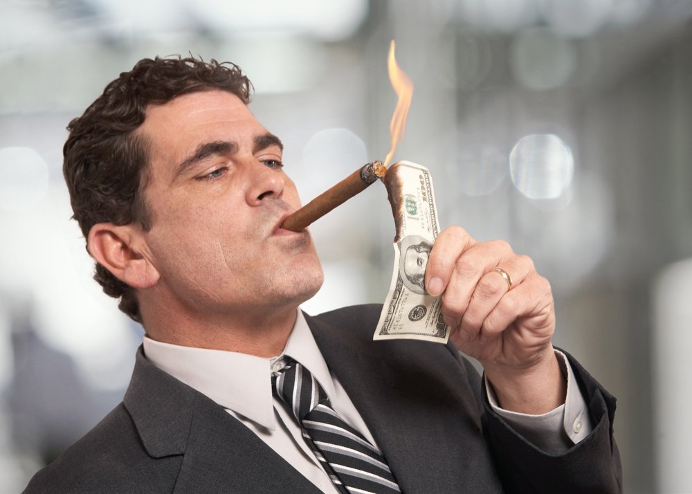 Un riche homme d'affaires qui allume des cigarettes avec un billet de 100 $. | Source : Shutterstock