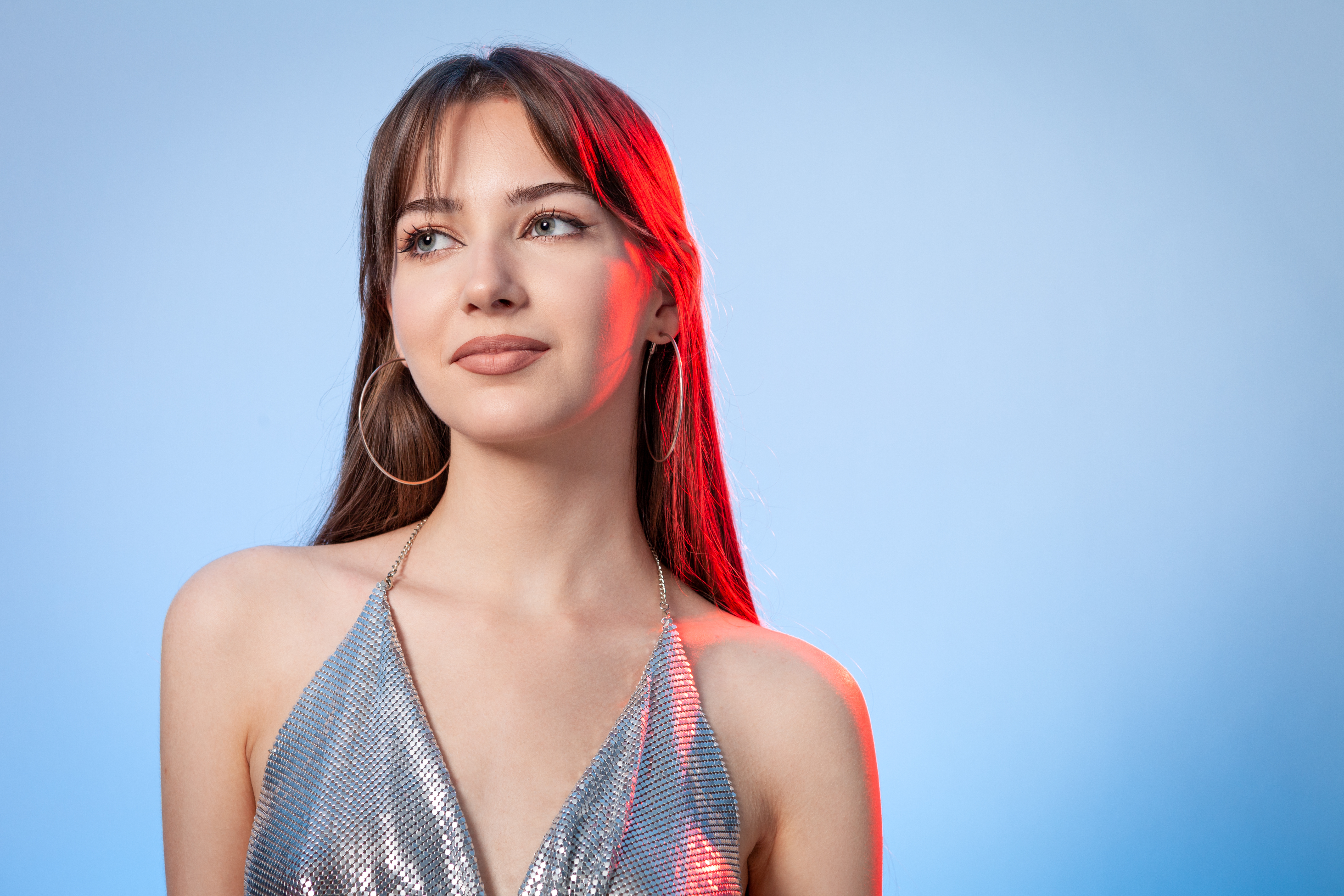 Portrait de studio d'une belle jeune femme blanche aux longs cheveux bruns sur fond bleu | Source : Getty Images