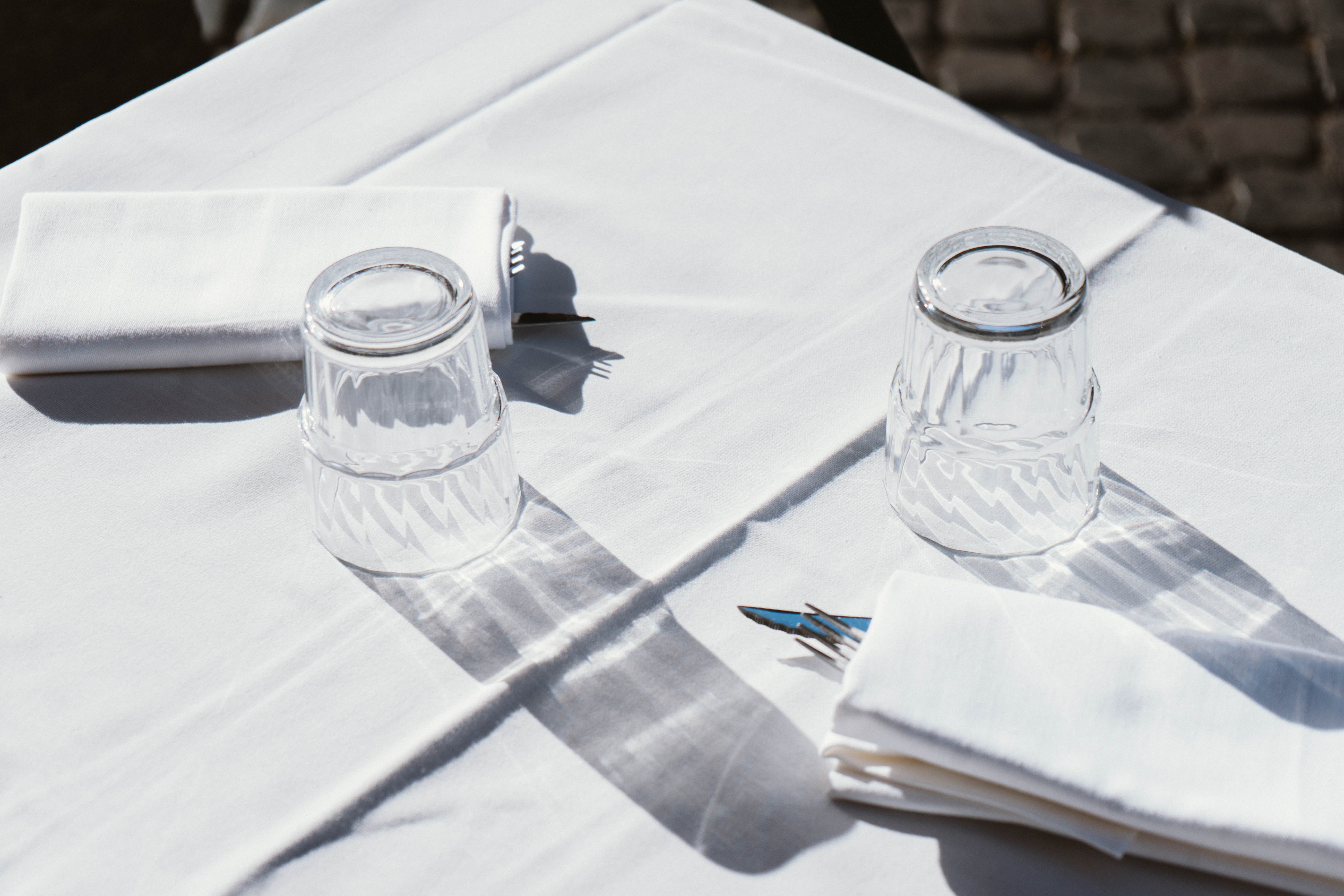 Une table à manger avec des verres et des serviettes. | Source : Pexels