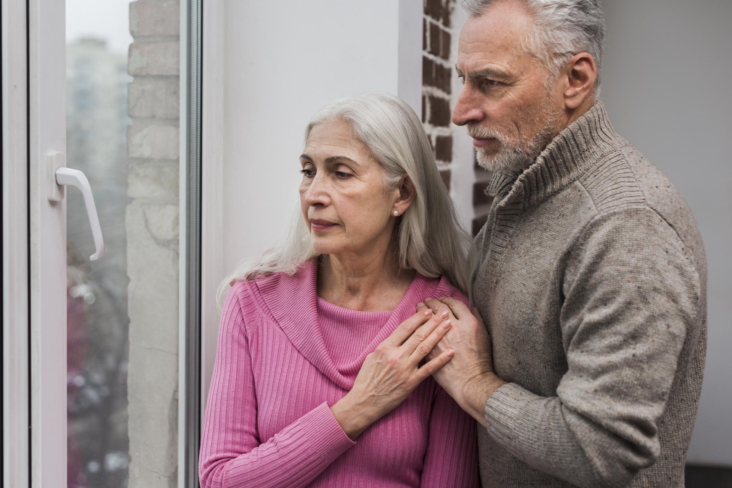 Un couple de personnes âgées qui regarde par la fenêtre | Source : Freepik