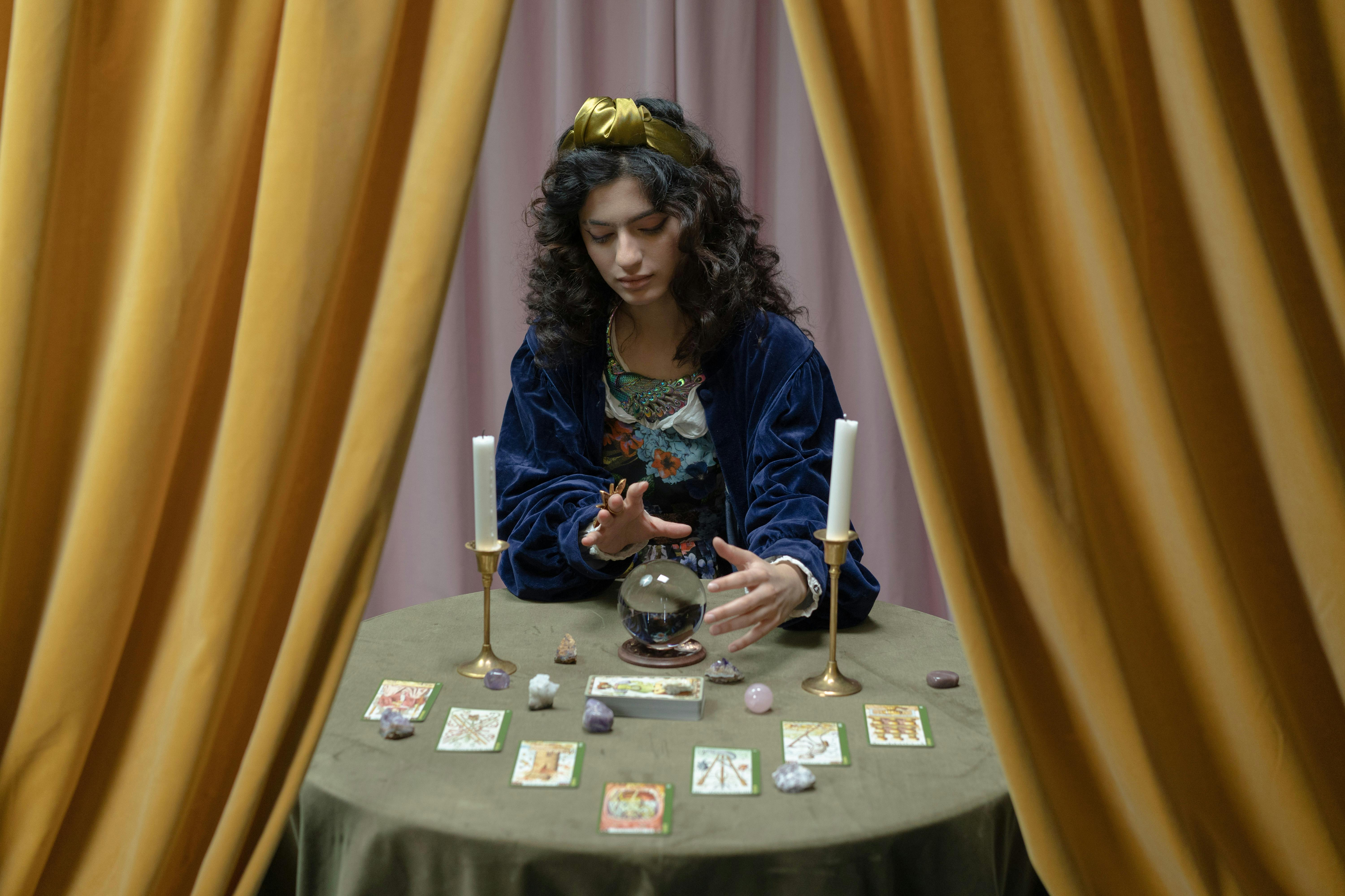 Une cartomancienne assise devant sa boule de cristal et ses cartes de tarot | Source : Pexels
