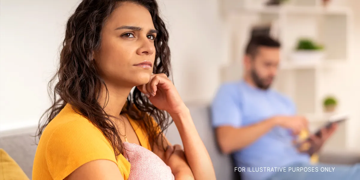 Une femme sérieuse perdue dans ses pensées alors qu'elle est assise à côté de son partenaire | Source : Shutterstock