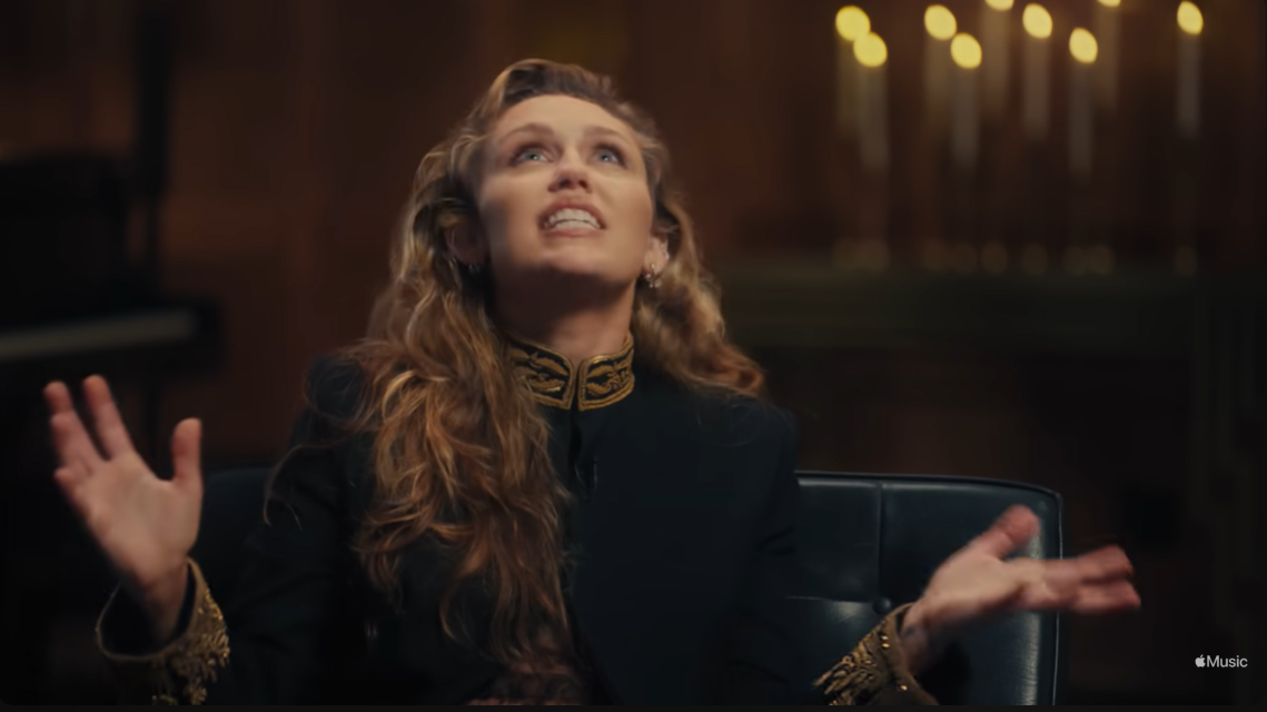 Miley Cyrus fait des gestes expressifs lors de son interview sur Apple Music, s'ouvrant sur le coût personnel derrière sa force vocale | Source : YouTube/AppleMusic