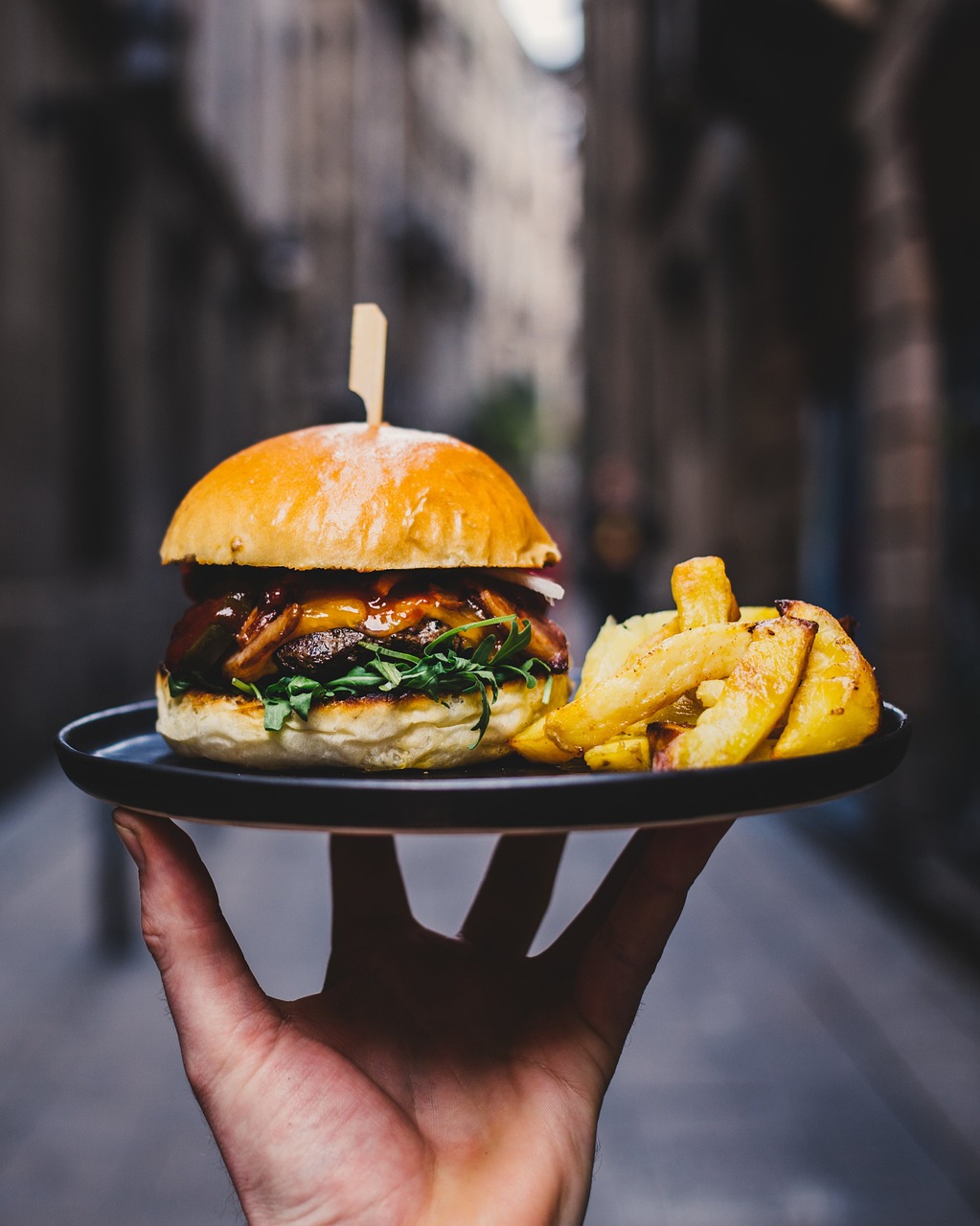 Un serveur s'apprête à servir une assiette avec un hamburger et des frites | Source : Pixabay