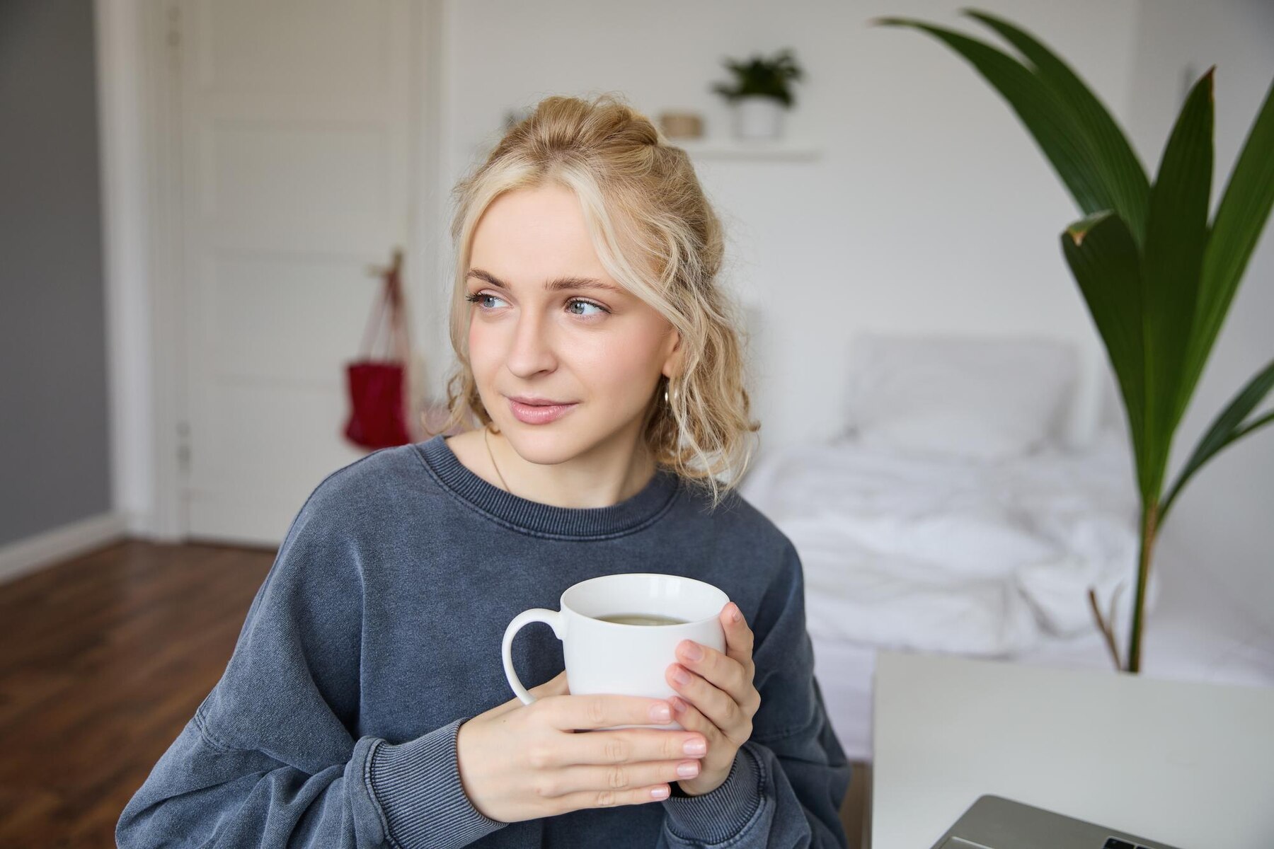 Une femme regarde sur le côté tout en buvant un café | Source : Freepik