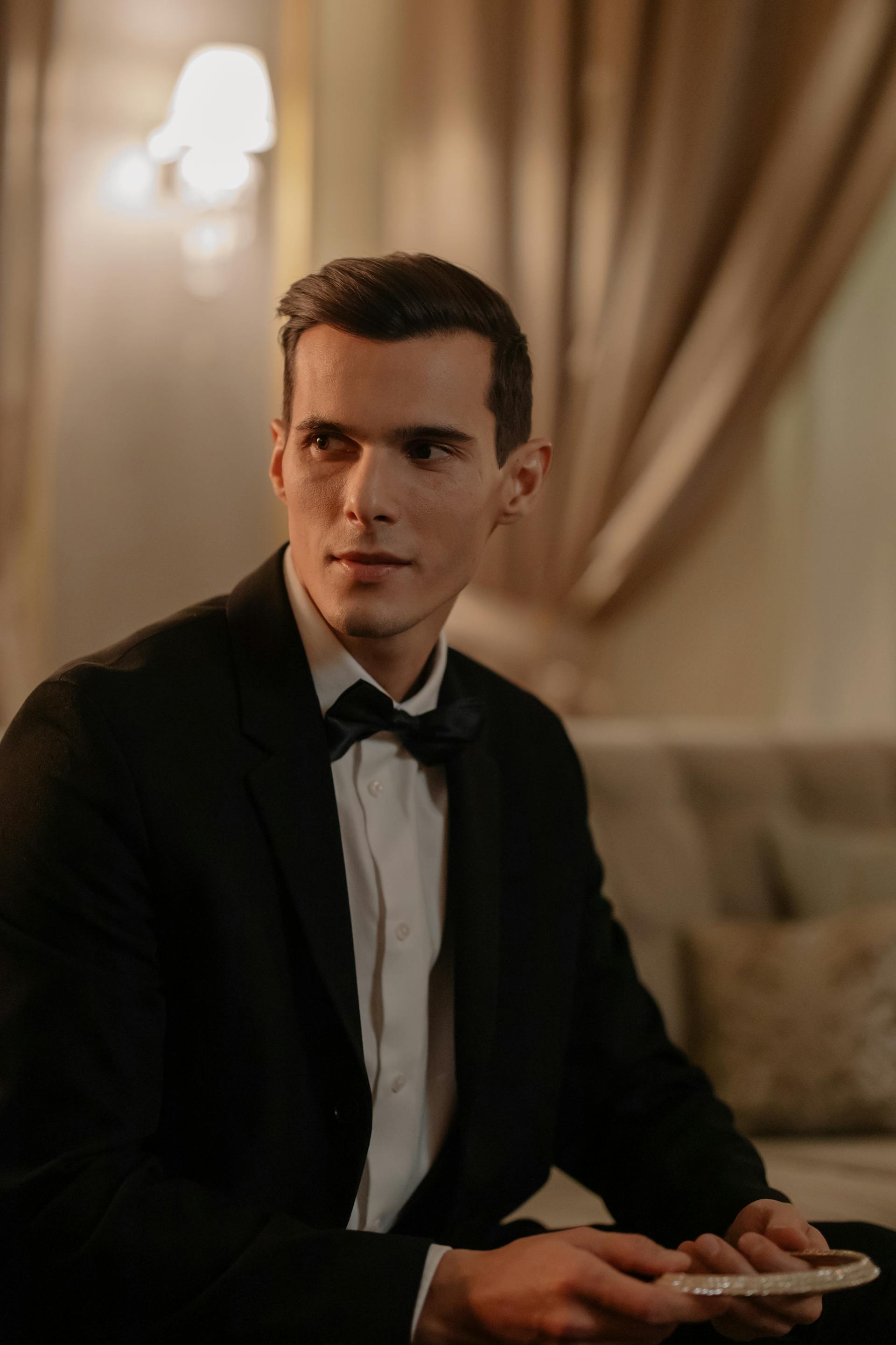 Un homme en costume noir assis sur le canapé et souriant | Source : Pexels