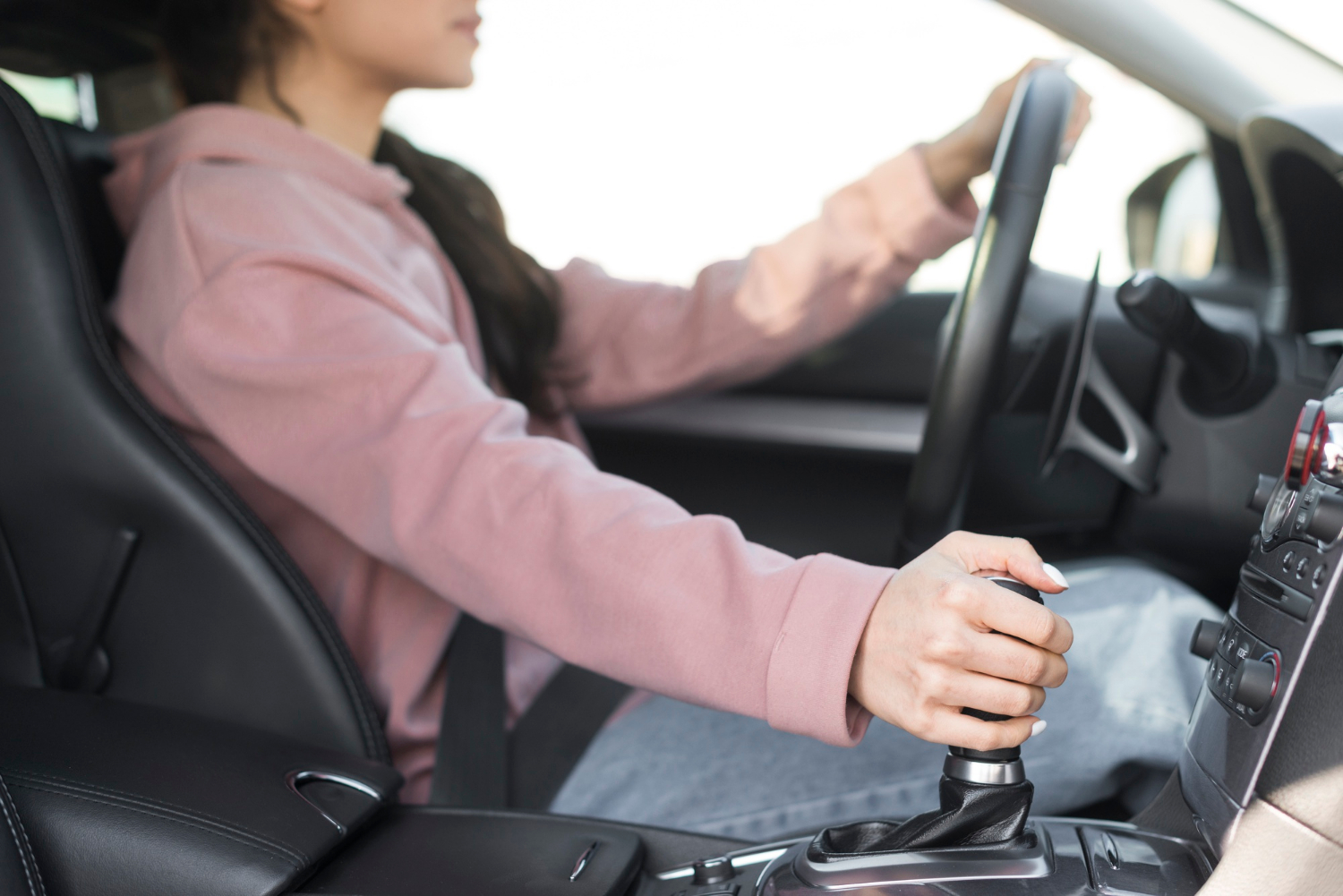 Une femme qui change de vitesse tout en conduisant sa voiture | Source : Freepik