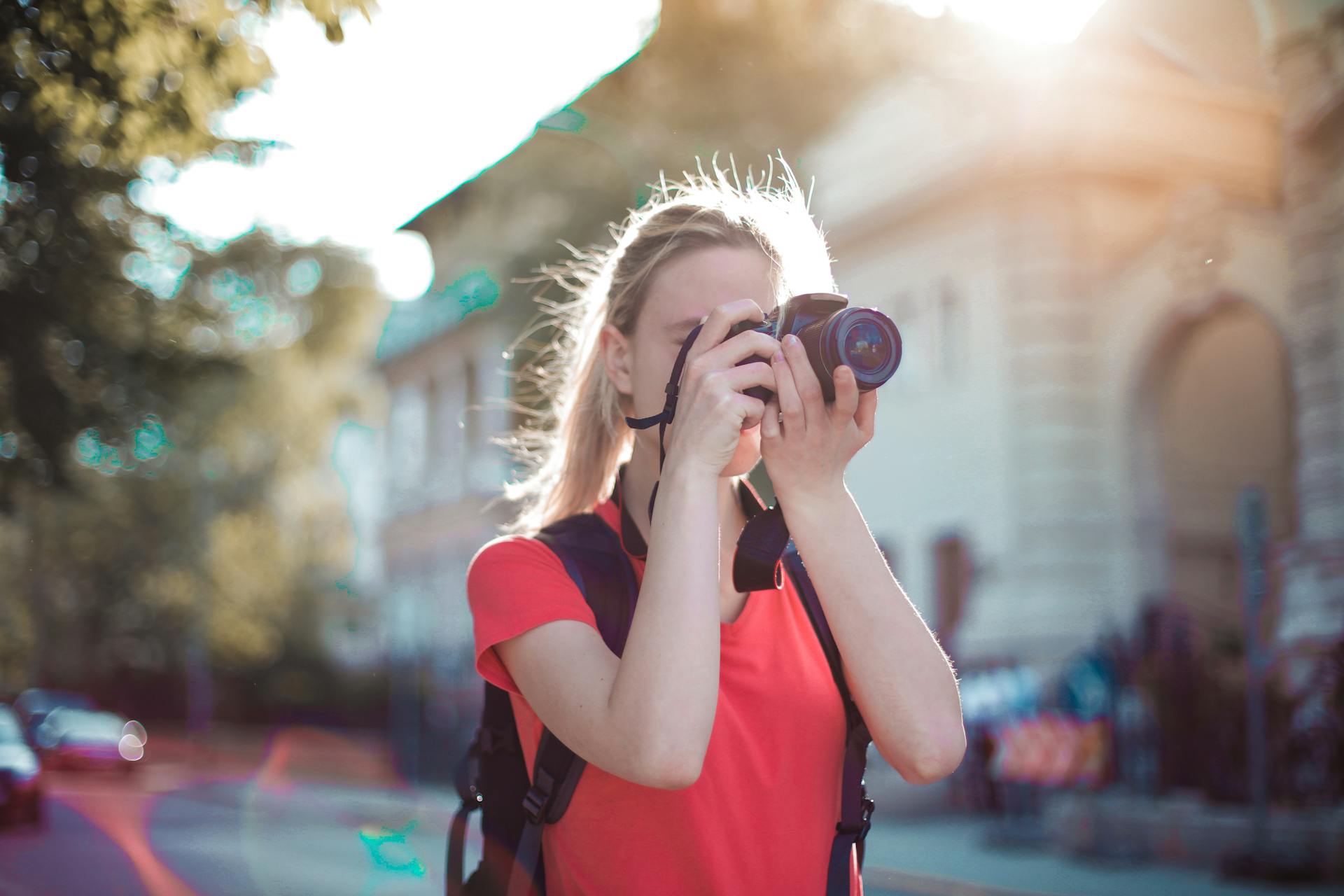 Une femme en train de cliquer sur une photo à l'aide d'un appareil photo reflex numérique | Source : Pexels