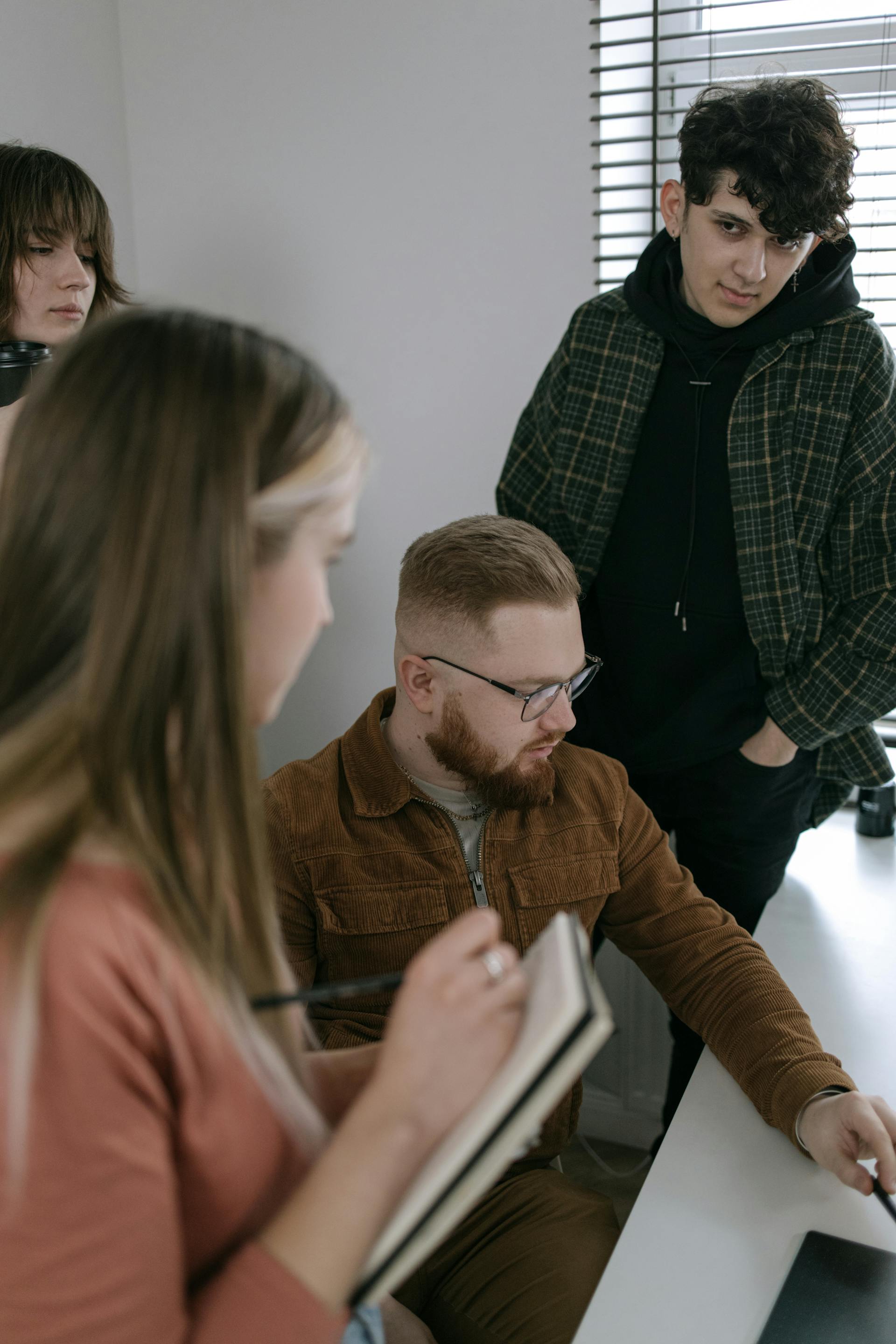 Un jeune homme regarde les autres membres de son équipe lors d'une discussion sur un projet de groupe | Source : Pexels