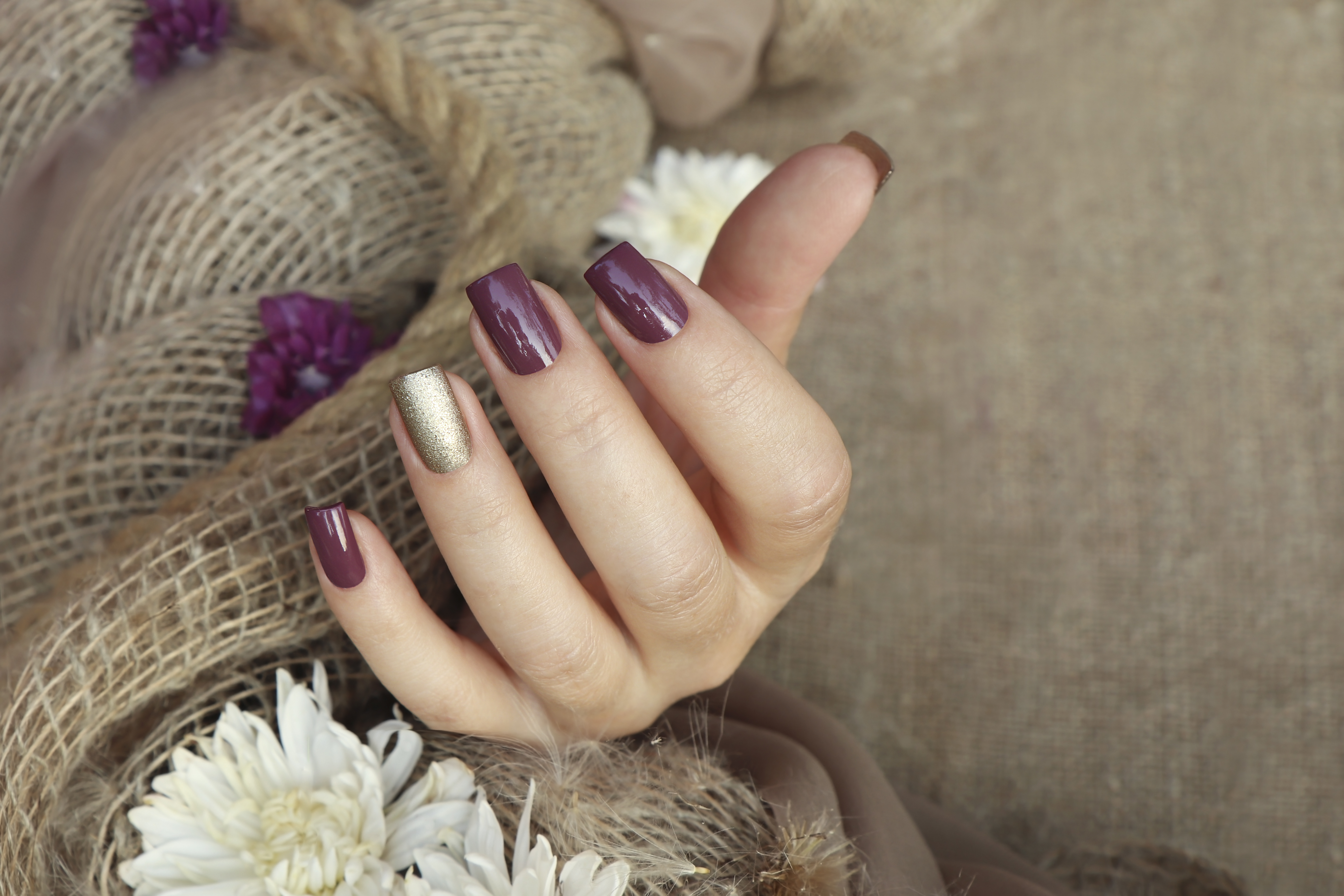 Une main féminine parée de teintes d'ongles prune et or | Source : Getty Images
