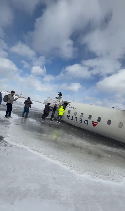 D'autres passagers sortent de l'avion Delta endommagé sur le sol enneigé tandis que d'autres personnes aident à l'évacuation | Source : Instagram.com/eggxit