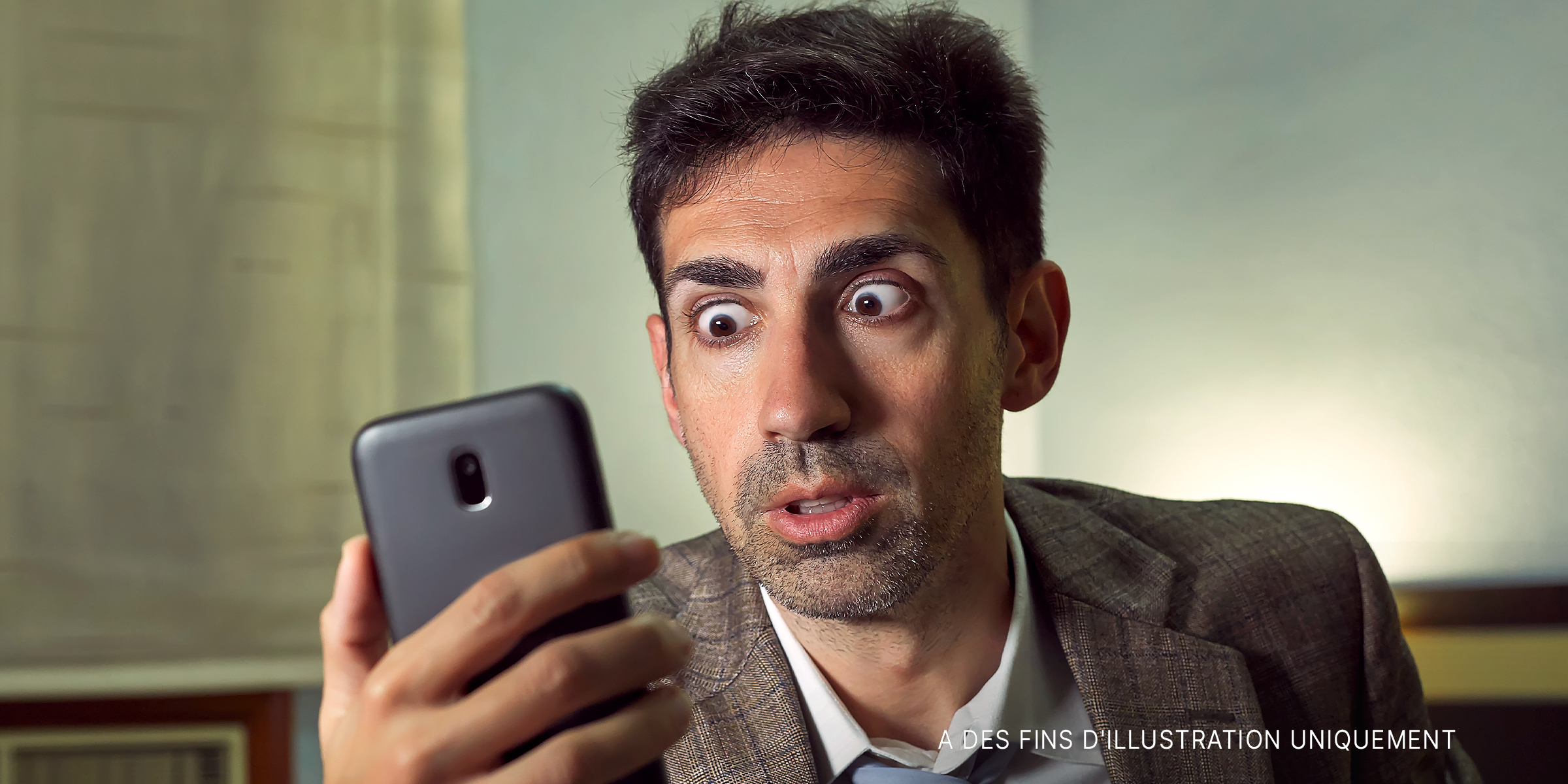 Un homme qui regarde son téléphone avec des yeux écarquillés | Source : Shutterstock