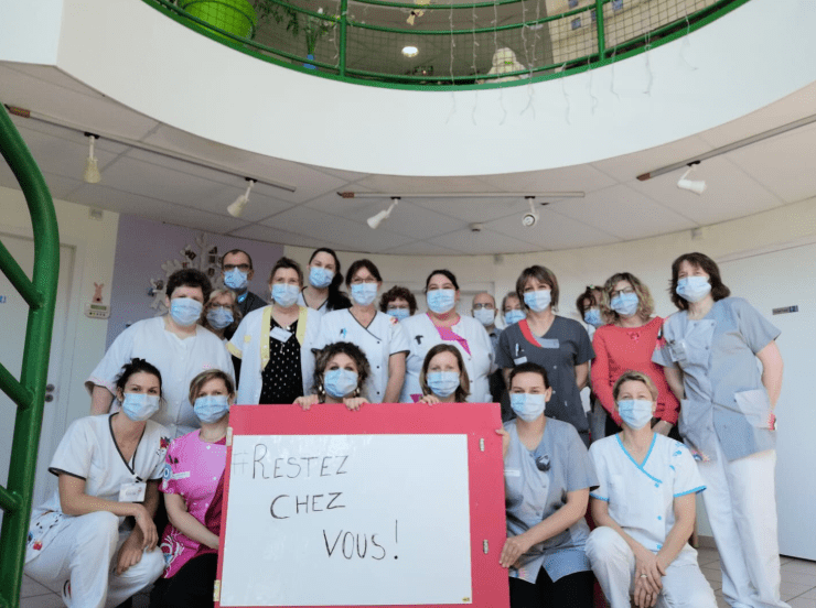 Des membres u personnels soignants portant des masques et une plaque "Restez chez vous" | Photo : YouTube/France24.