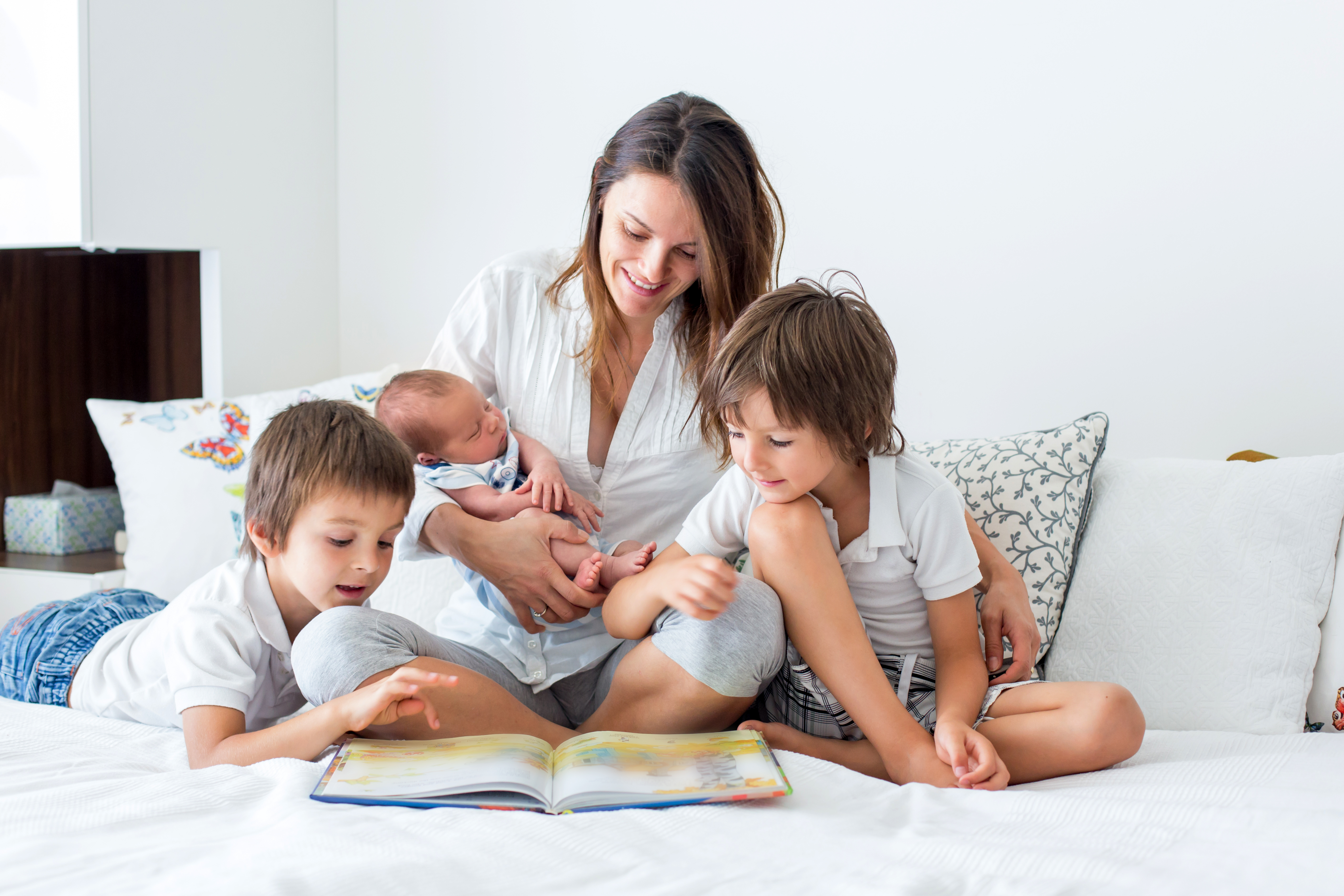 Une jeune mère lisant un livre à ses trois enfants | Source : Shutterstock