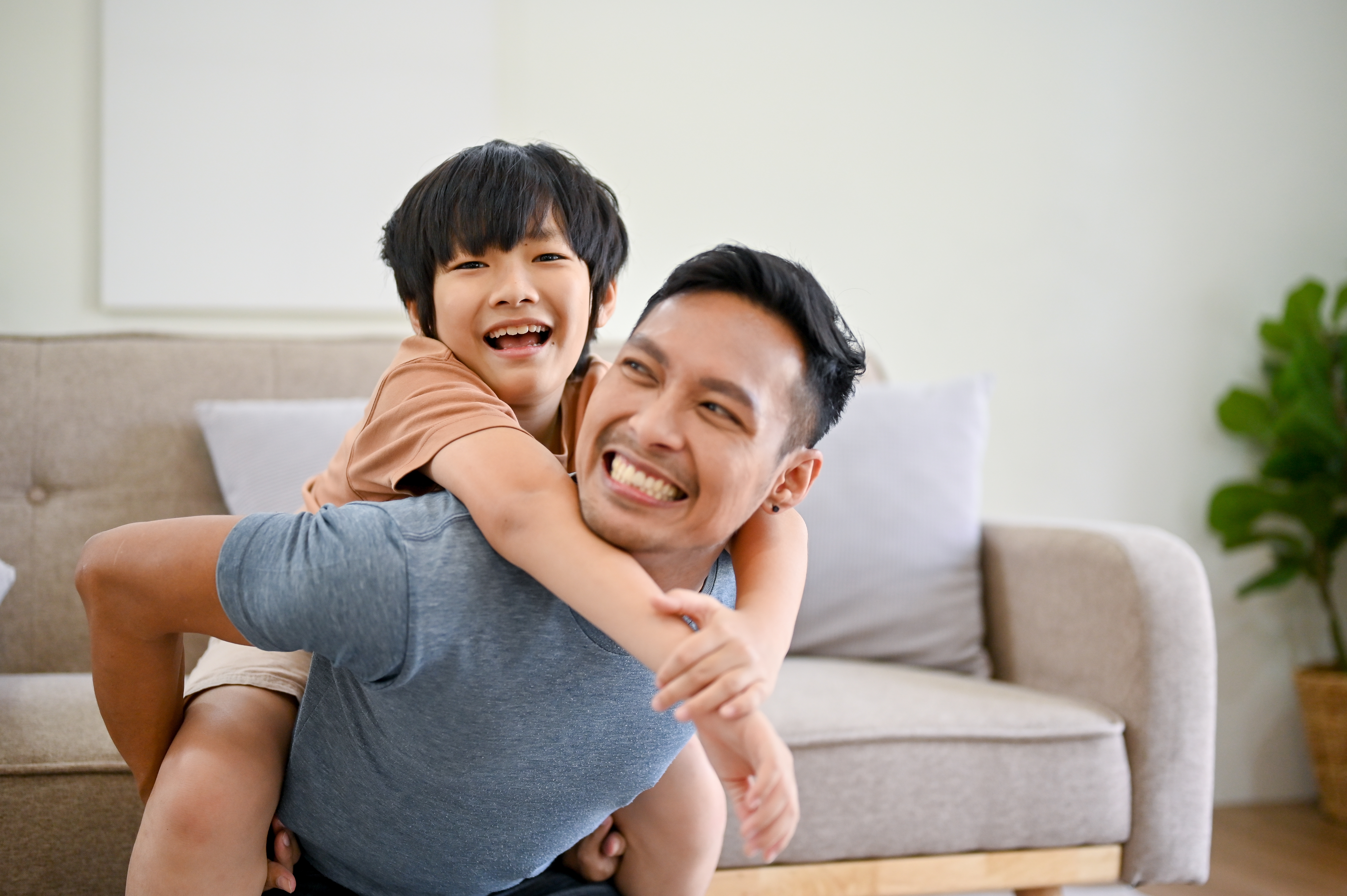 Fils asiatique sur le dos de son père, souriant | Source : Shutterstock