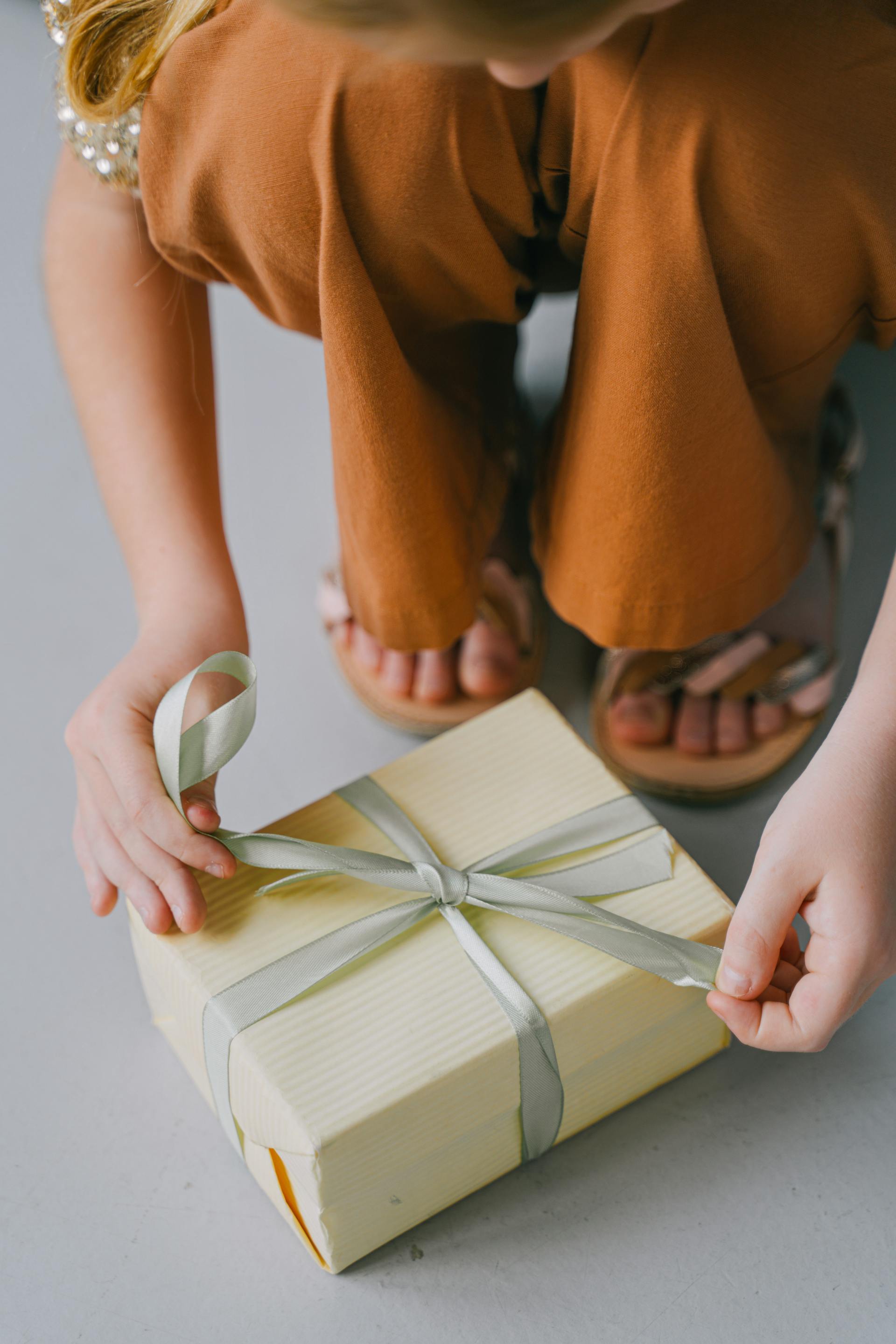 Une femme noue le ruban d'un paquet cadeau | Source : Pexels