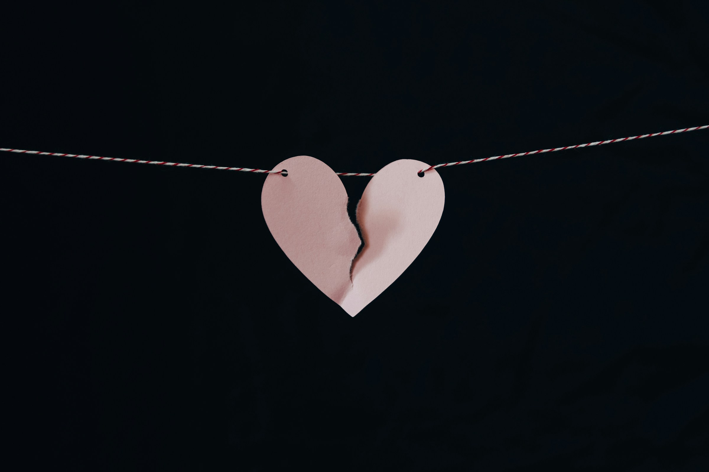 Un cœur en papier brisé accroché à un fil de fer | Source : Unsplash
