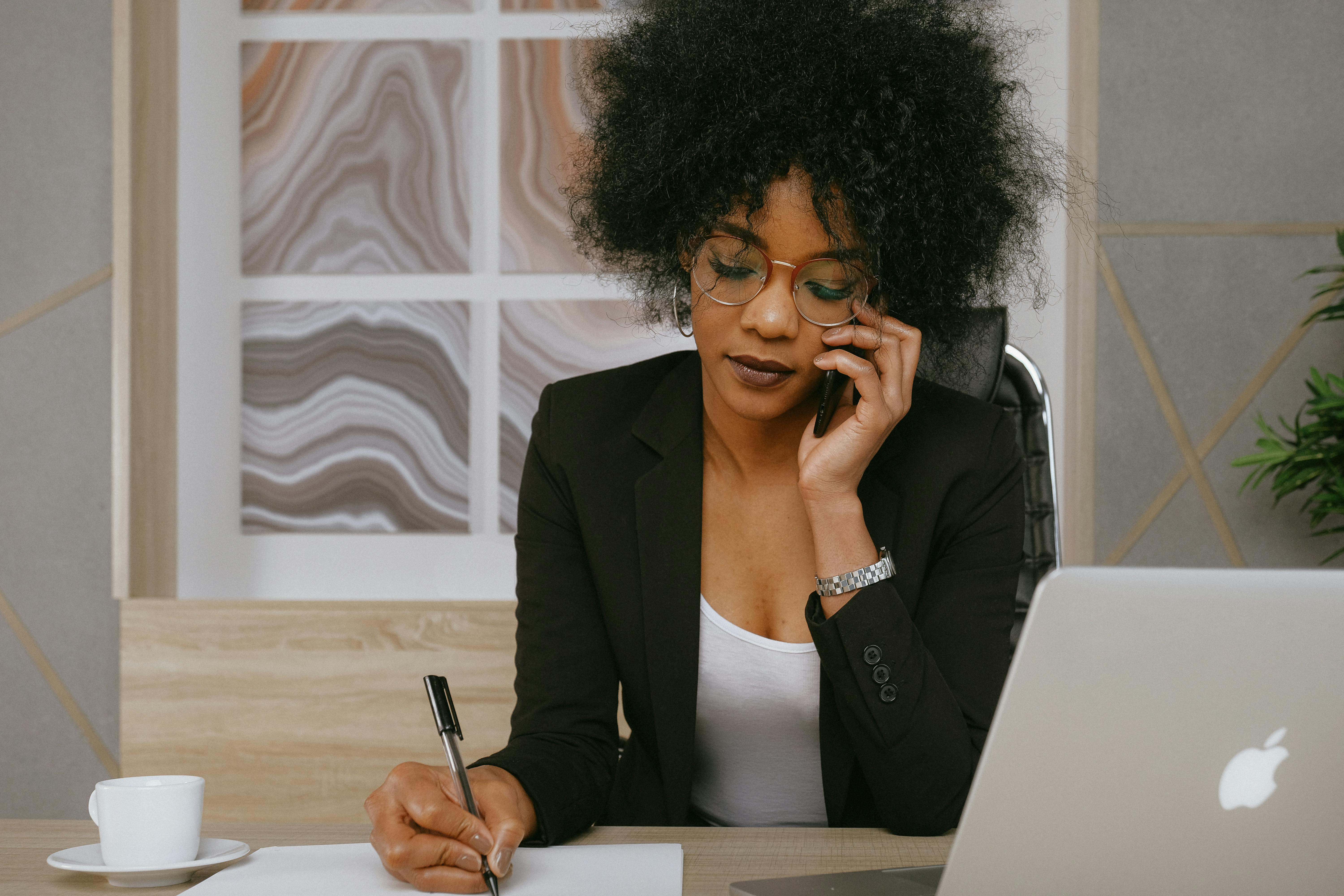 Une femme assise à son bureau parlant au téléphone | Source : Pexels