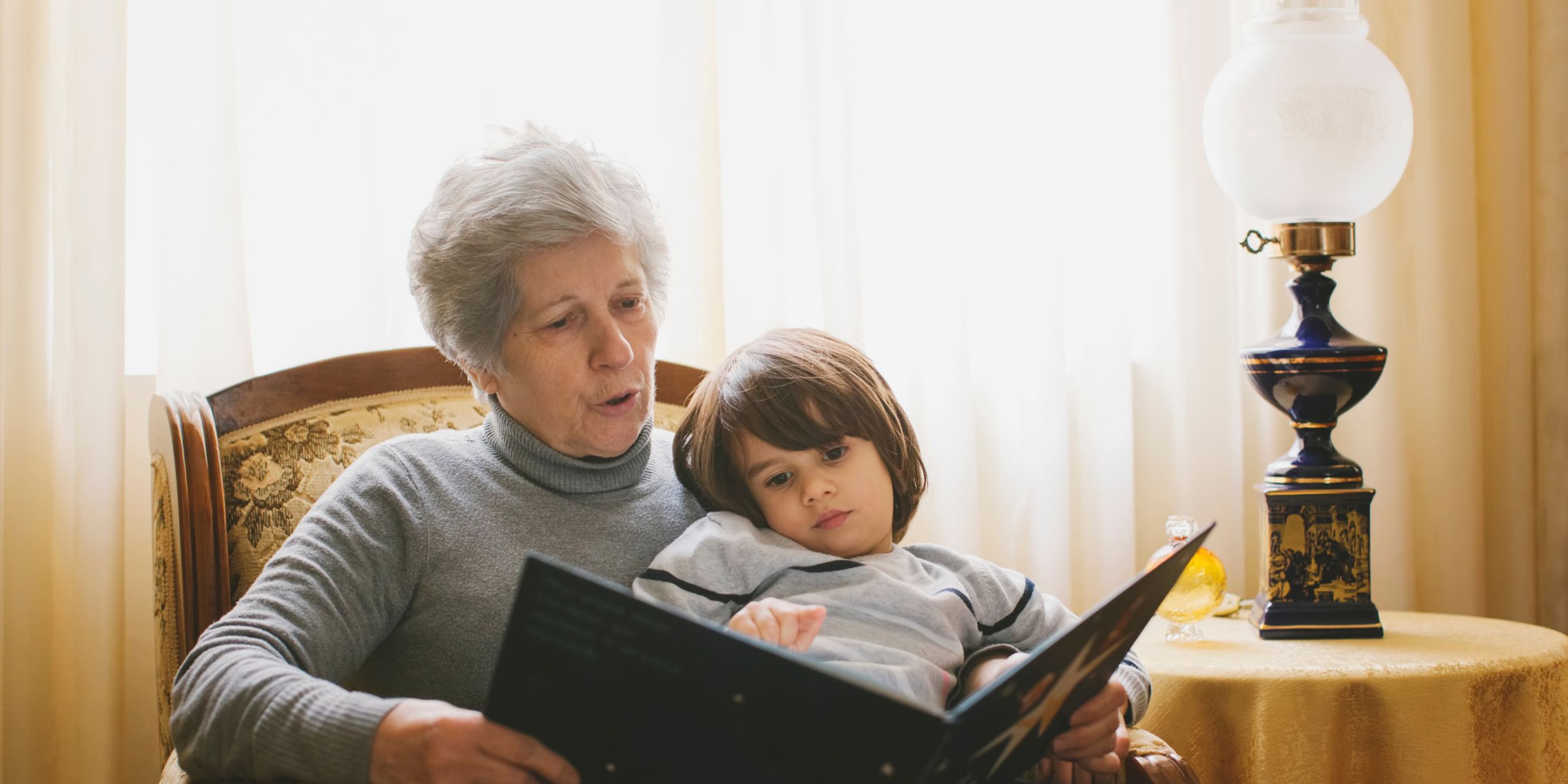 Un petit garçon en train de lire un livre avec sa grand-mère | Source : Getty Images