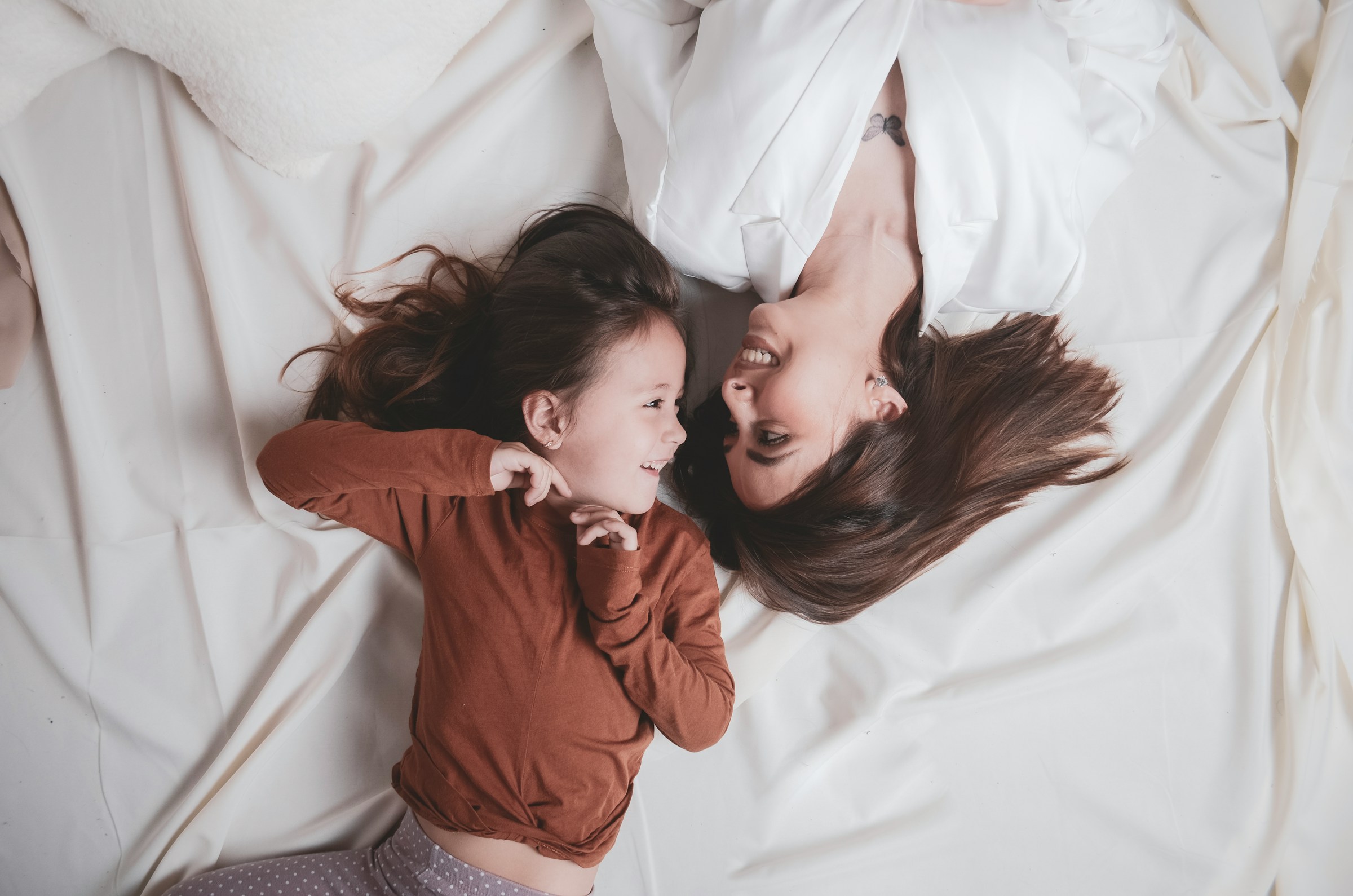Une femme et une petite fille se regardant l'une l'autre alors qu'elles sont allongées dans leur lit | Source : Unsplash