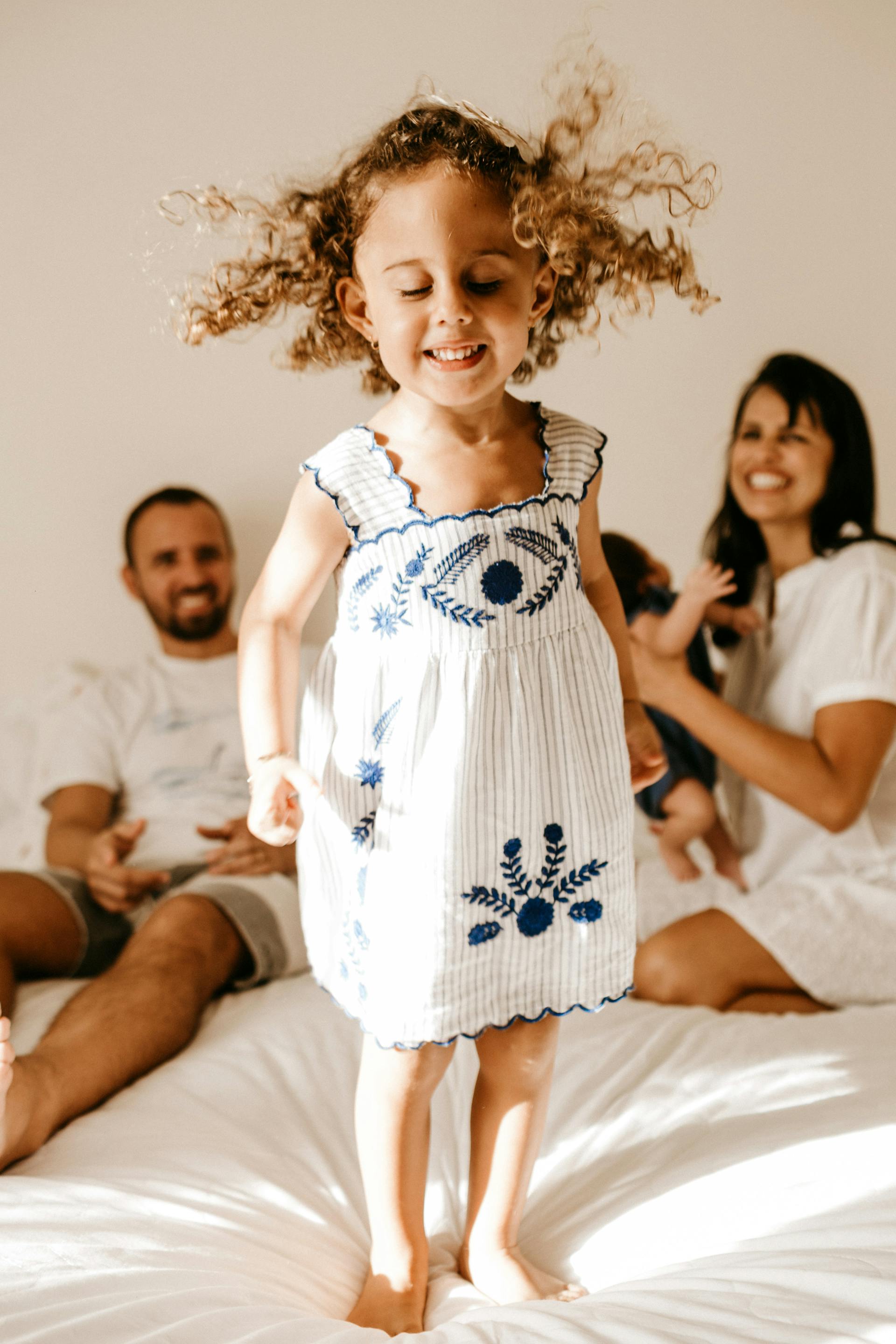 Une petite fille heureuse debout sur un lit | Source : Midjourney