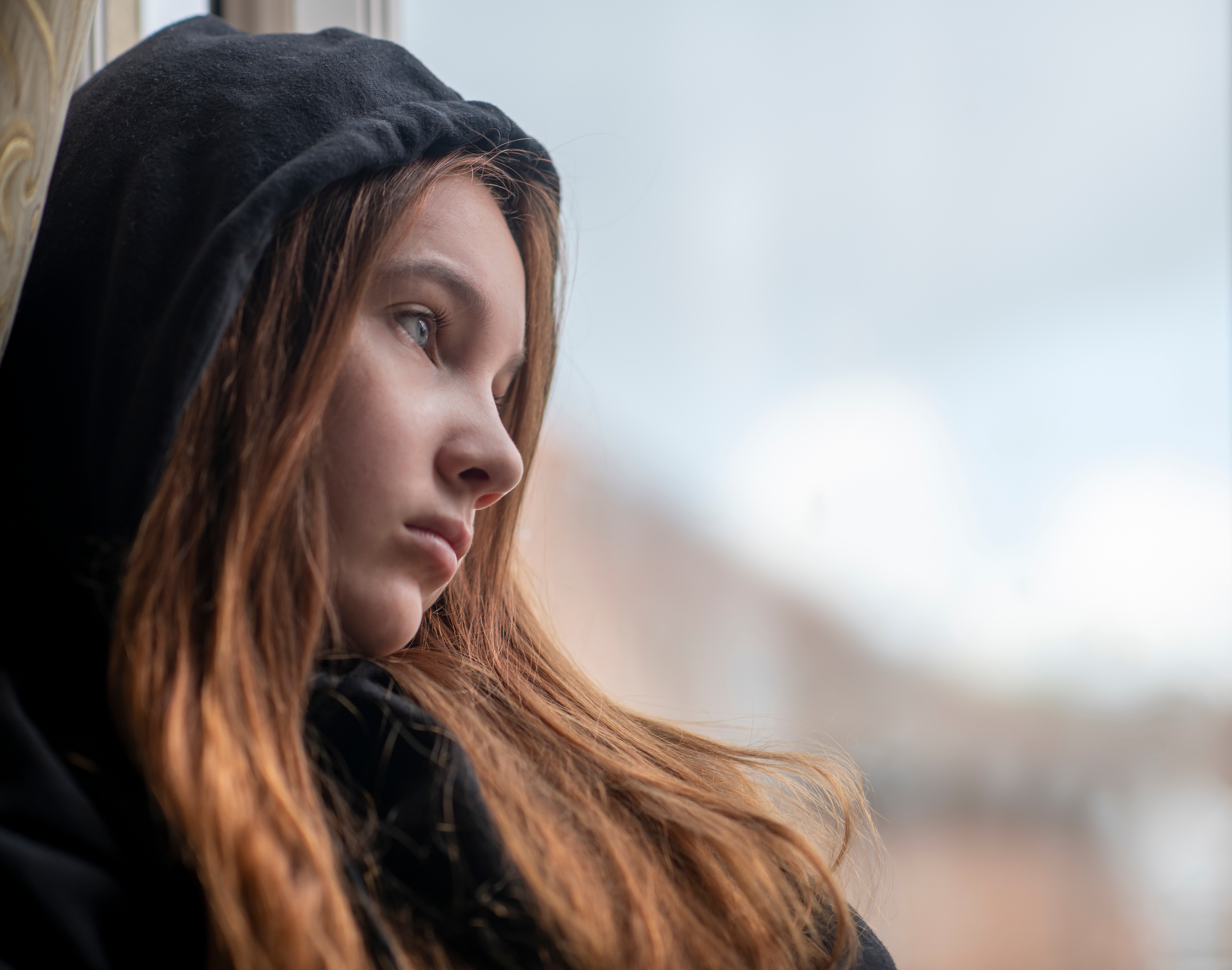 Une adolescente triste debout près d'une fenêtre | Source : Shutterstock