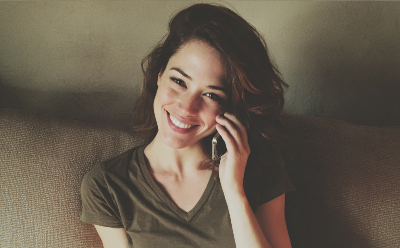 Une femme souriante qui parle au téléphone | Source : Midjourney